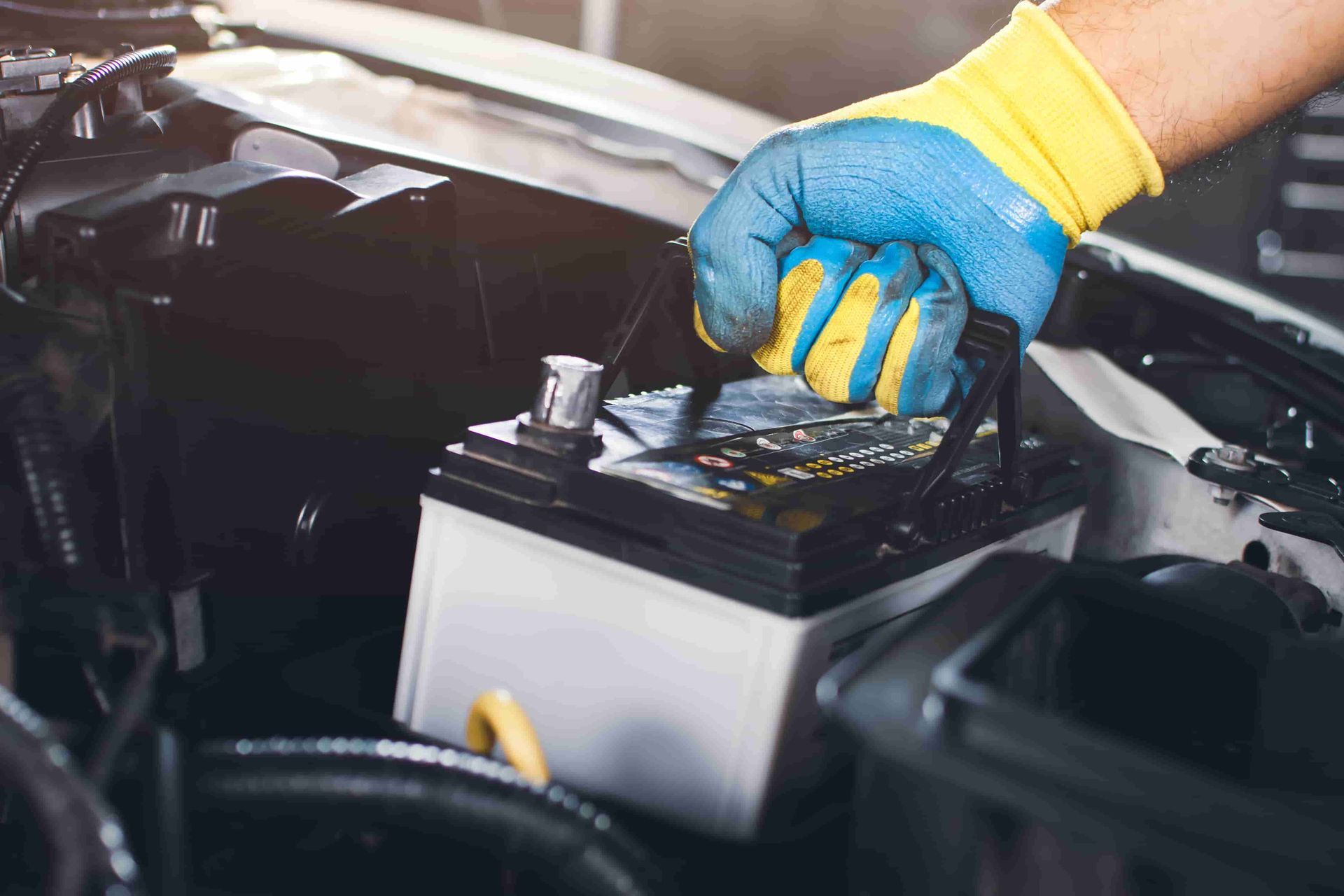 A Person Is Holding A Screwdriver Over A Car Battery — Auto Elect In Parramatta Park, QLD