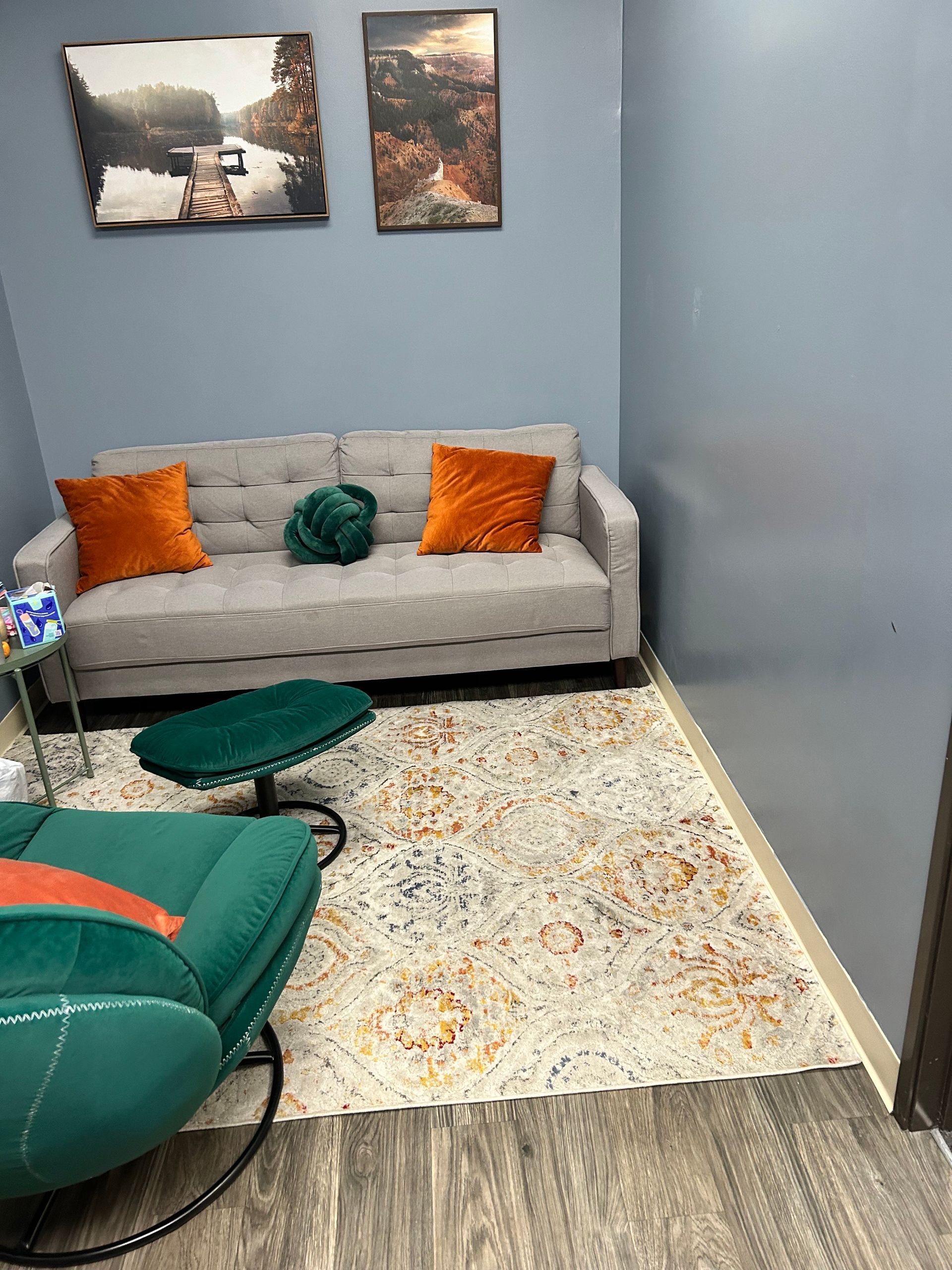a play area at Peck Counseling with a rug , chairs , a table and a window .