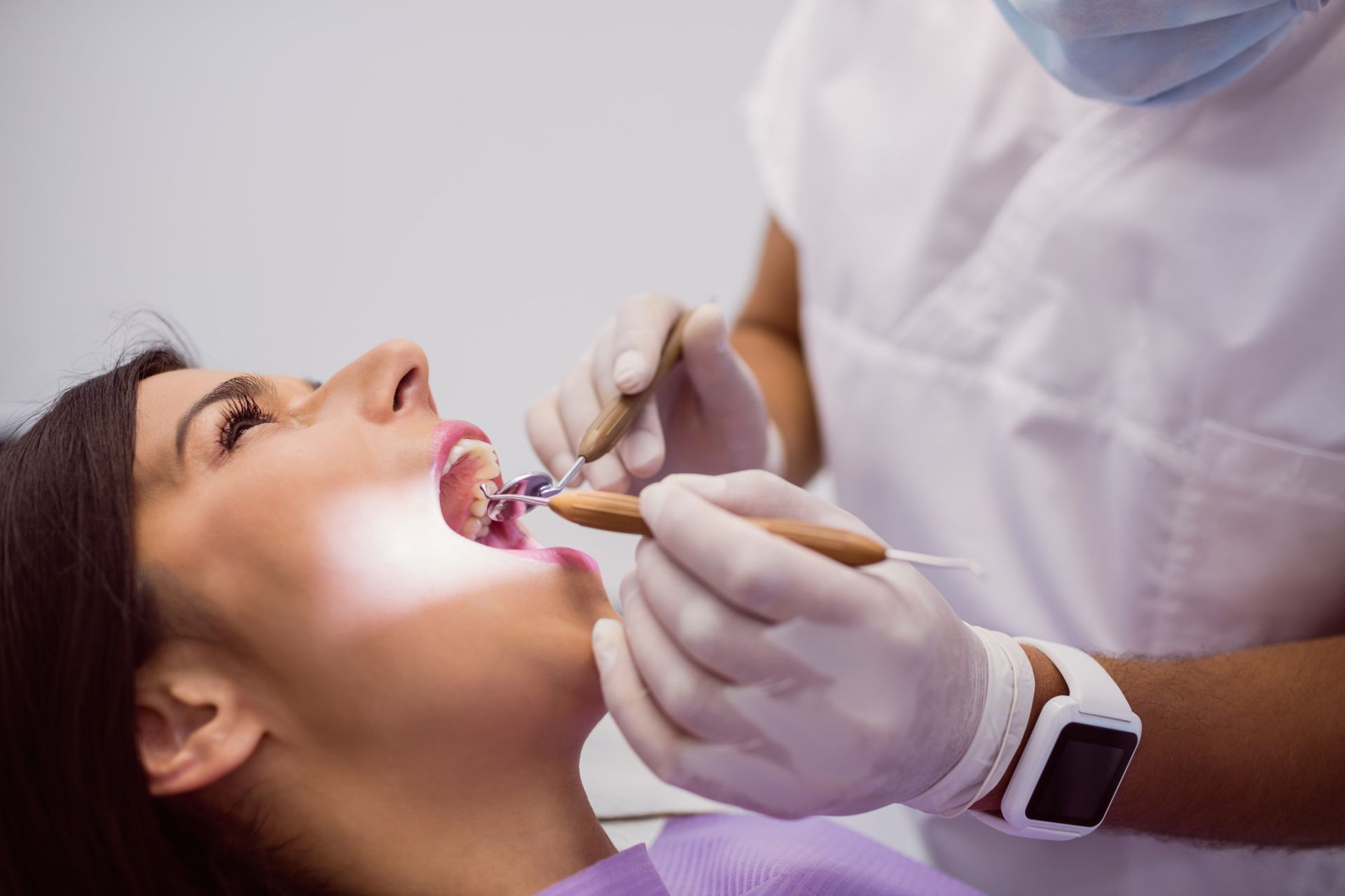 Dentista examinando la boca de un paciente con aparatos ortopédicos; entorno clínico.