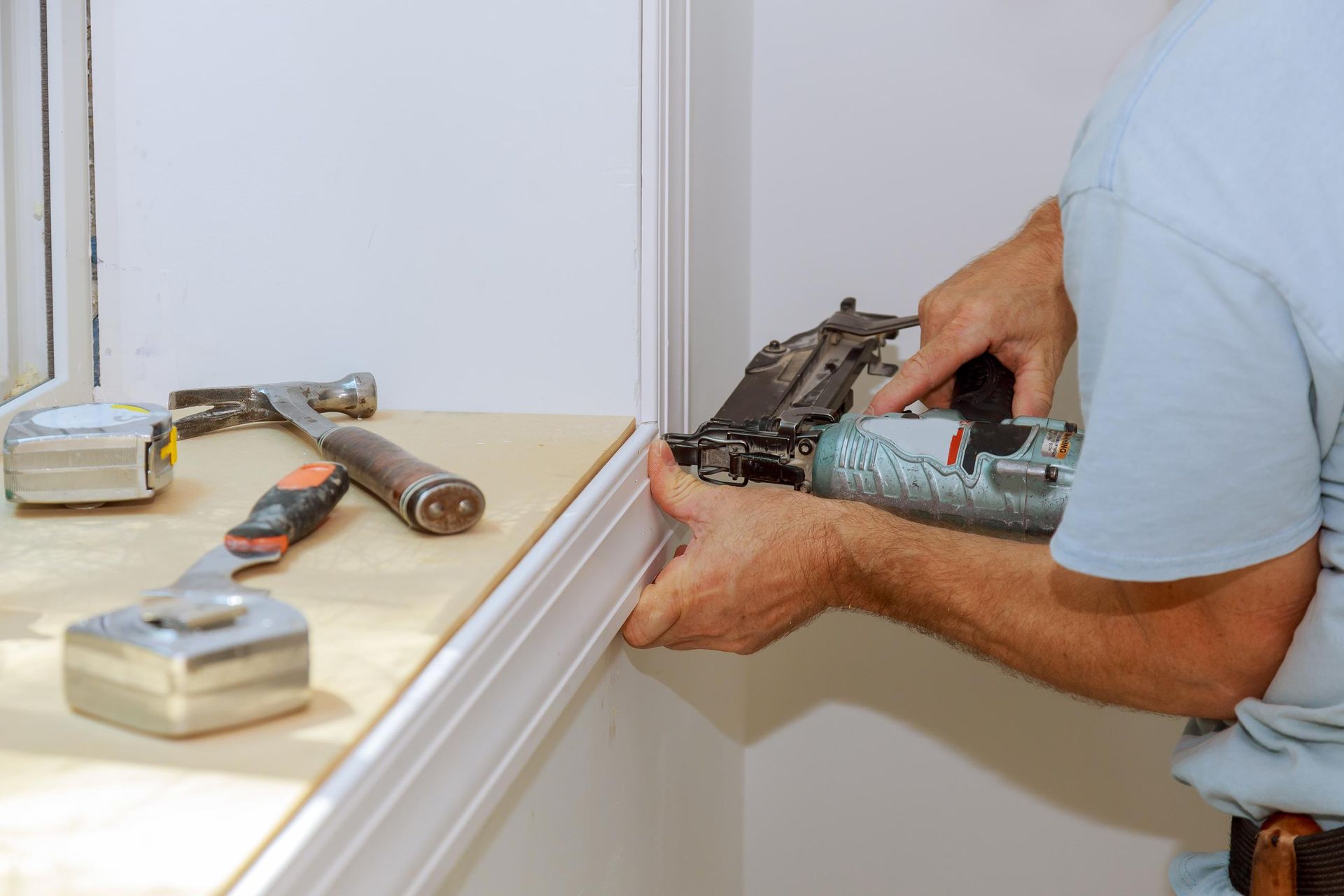 Worker installing trim around a window molding.