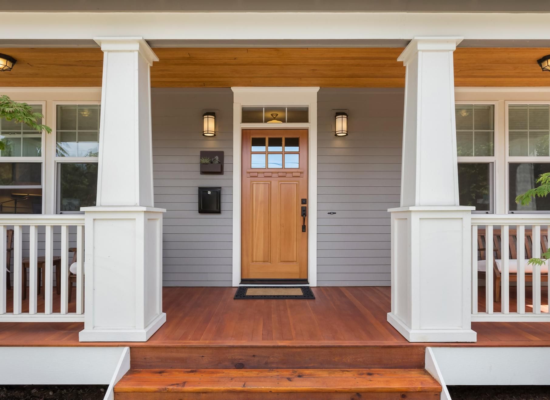 The front porch of a house with a wooden door and steps.