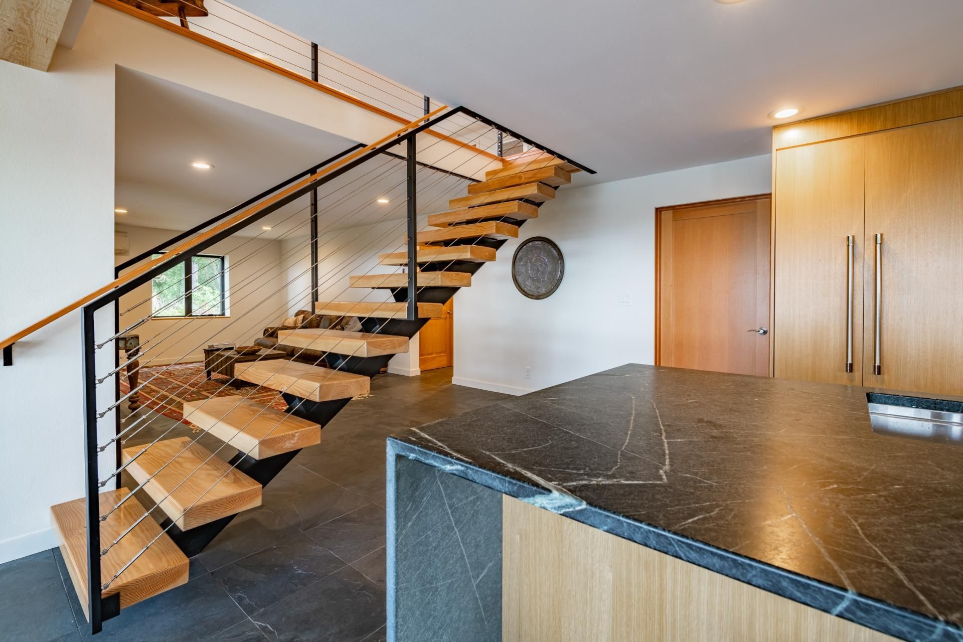 A wooden staircase with a black railing is leading up to the second floor of a house.