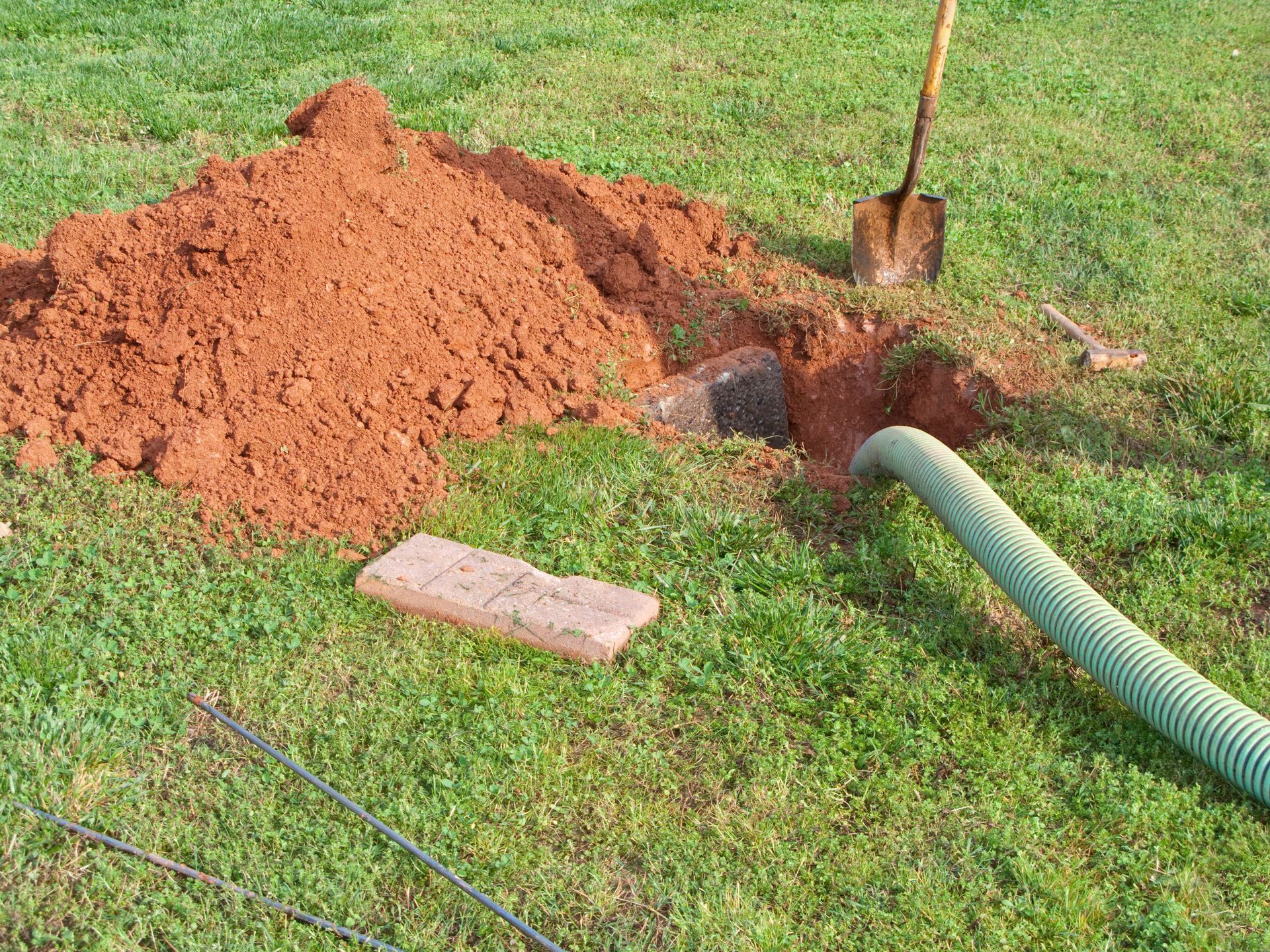 Seen here is a dug out open septic tank being pumped out. All the required tools are laying in the
y