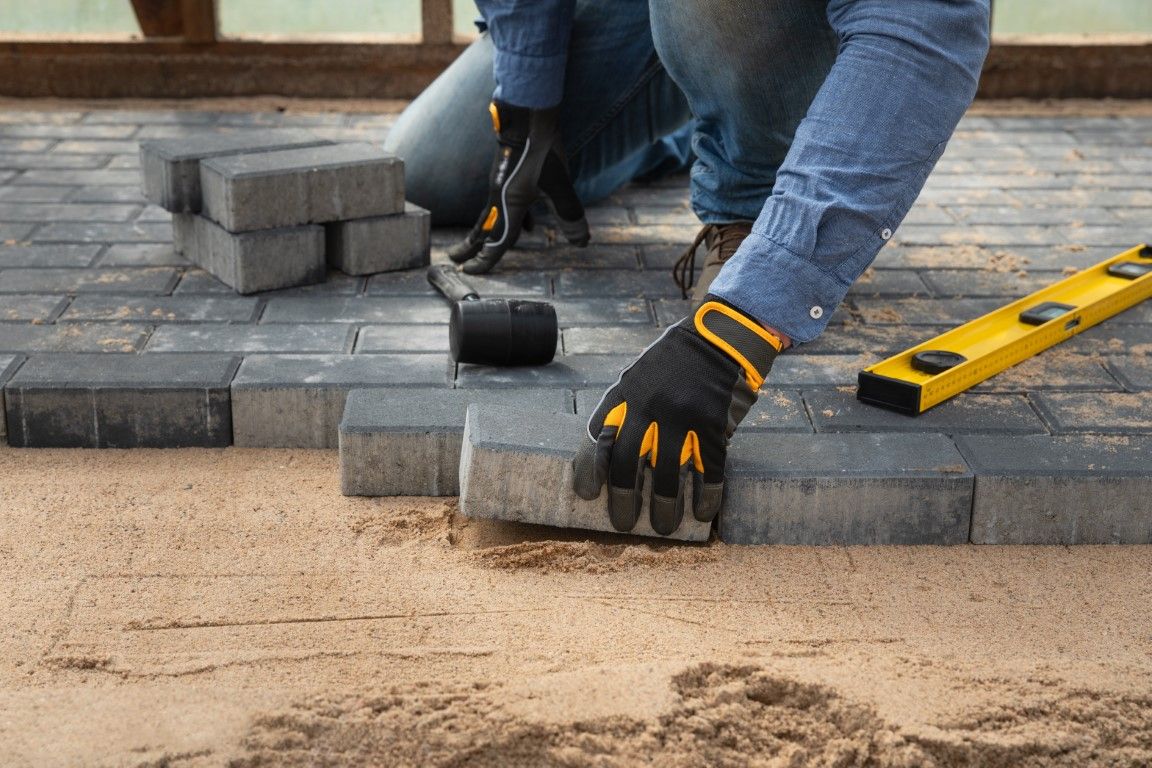 Close-up Photo of installer fitting paver stones into place.