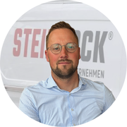 Daniel Neeland steht vor einem weißen Lieferwagen mit roter Aufschrift.