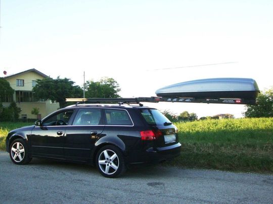 Una station wagon nera parcheggiata a bordo strada con una barca dal tetto blu su un rimorchio alle sue spalle.