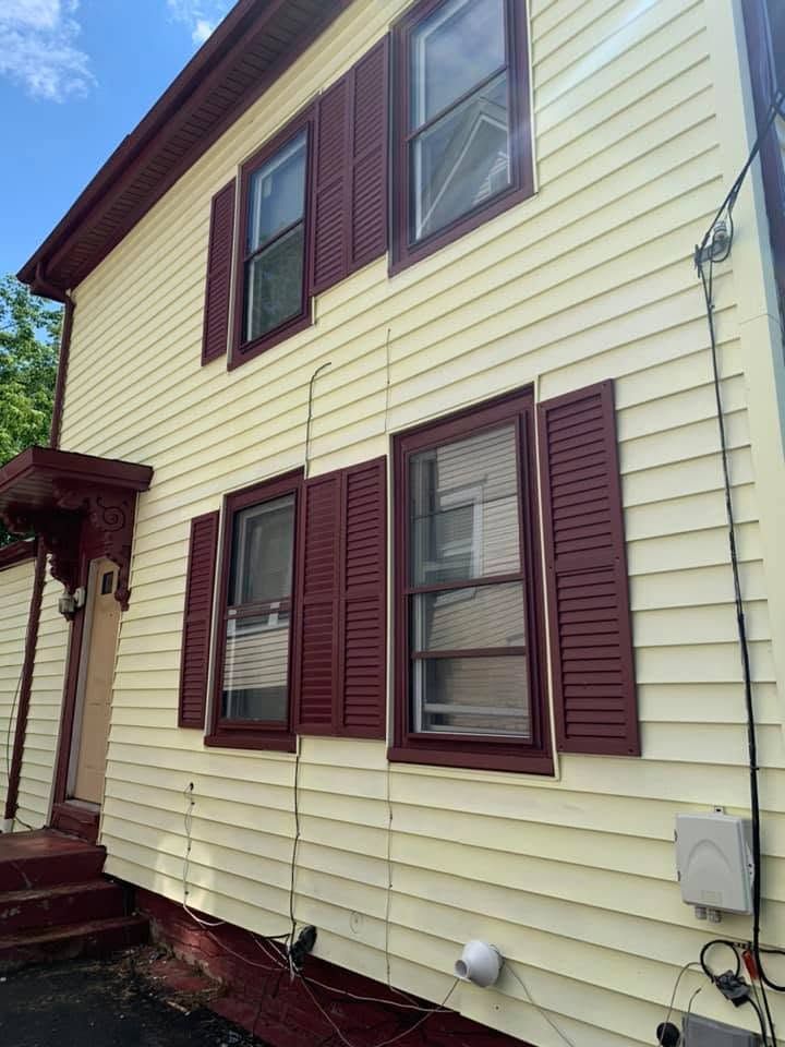 Two-story cream house with maroon shutters and front porch, viewed from the side