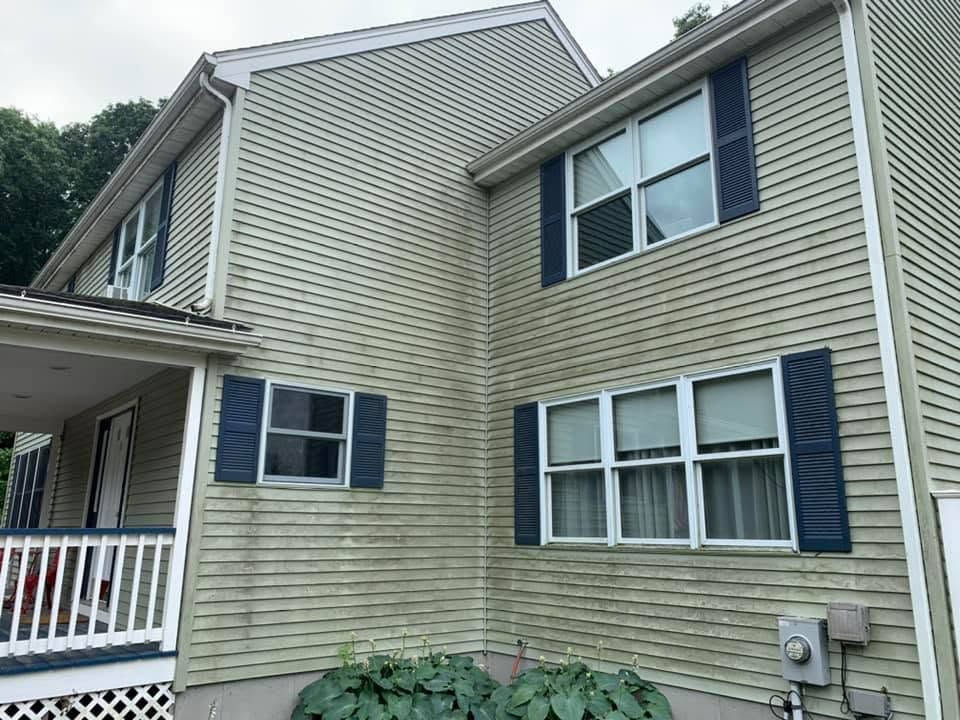 Beige-sided townhouse exterior with blue shutters and white porch railing