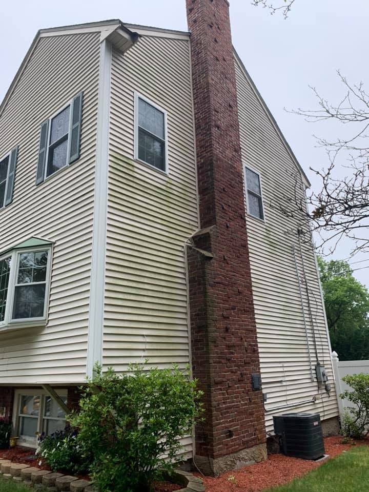 Tall beige house with a brick chimney and white-trimmed windows, viewed from the side outdoors.