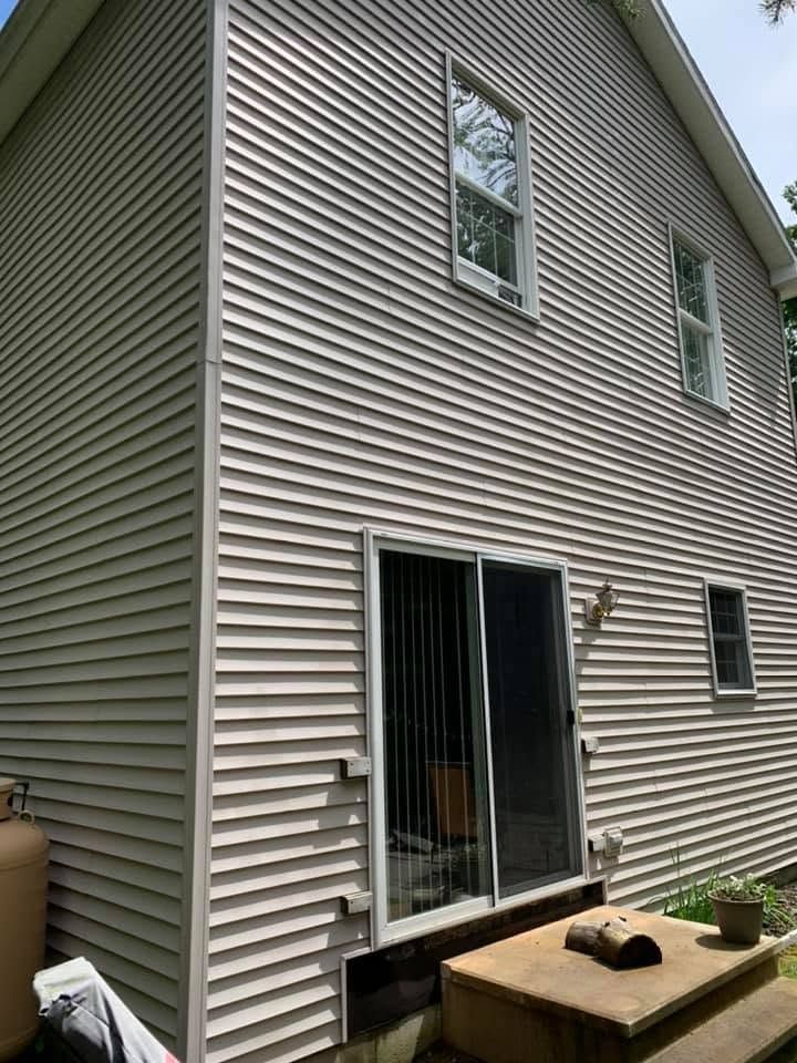 Side view of a beige house with sliding glass door, windows, and a small patio area.