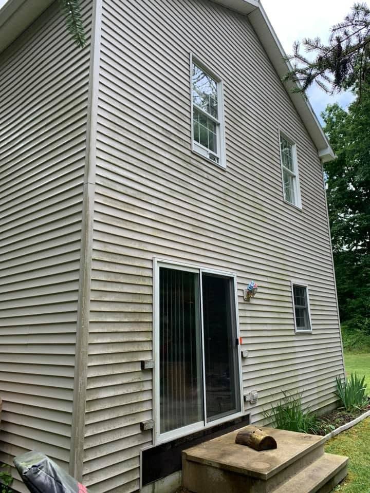 Side view of a beige two-story house with sliding glass doors and a small wooden deck.
