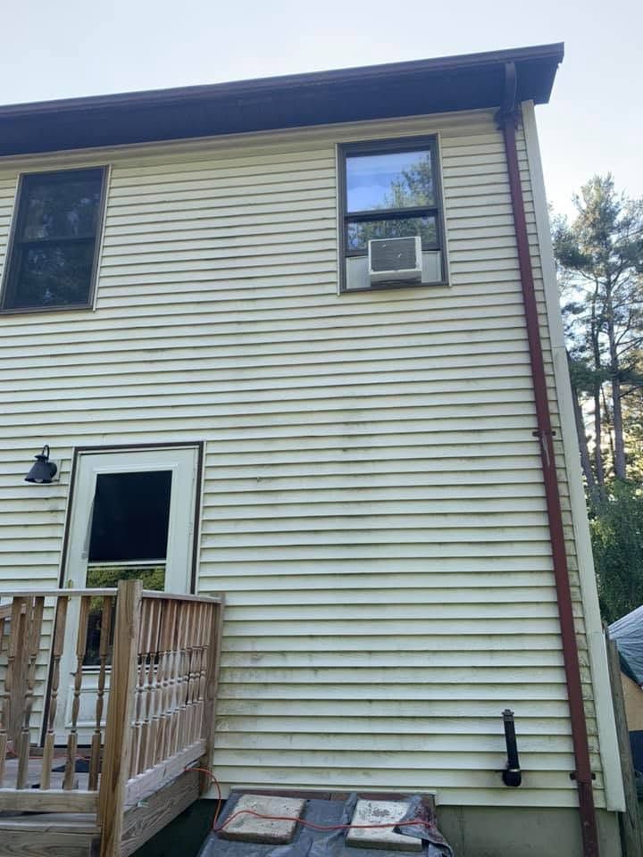 Two-story house exterior with beige siding, a porch, and a window air conditioner.