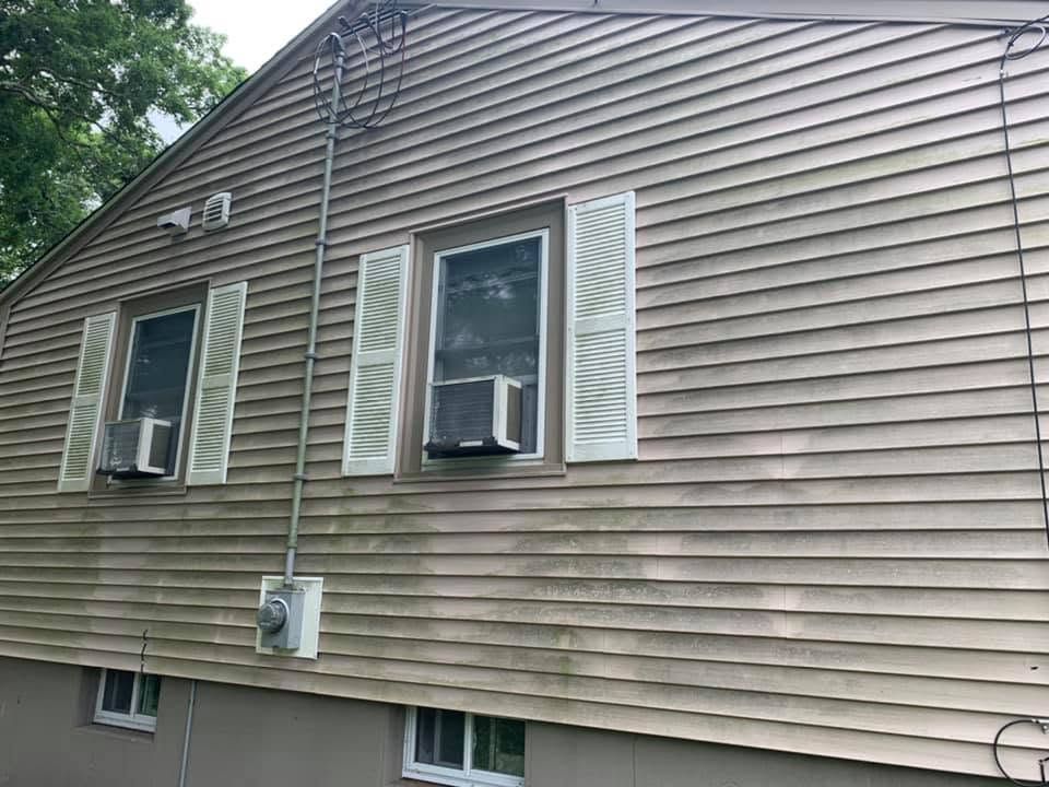 Side view of beige vinyl-sided house with several windows and window air conditioners