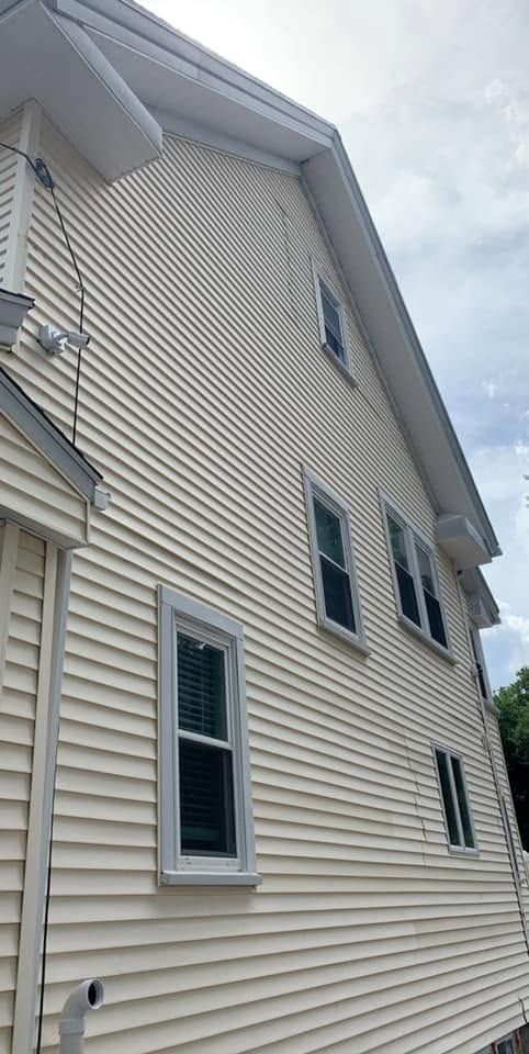 White-sided house exterior with several windows and a roofline viewed from below