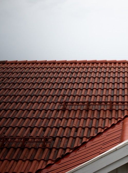 Red clay tile roof against a pale sky with a white roof edge visible