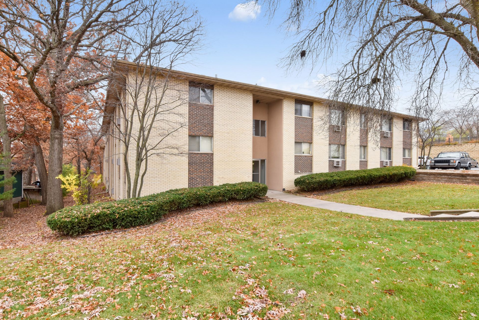 A large apartment building with a lush green lawn in front of it.