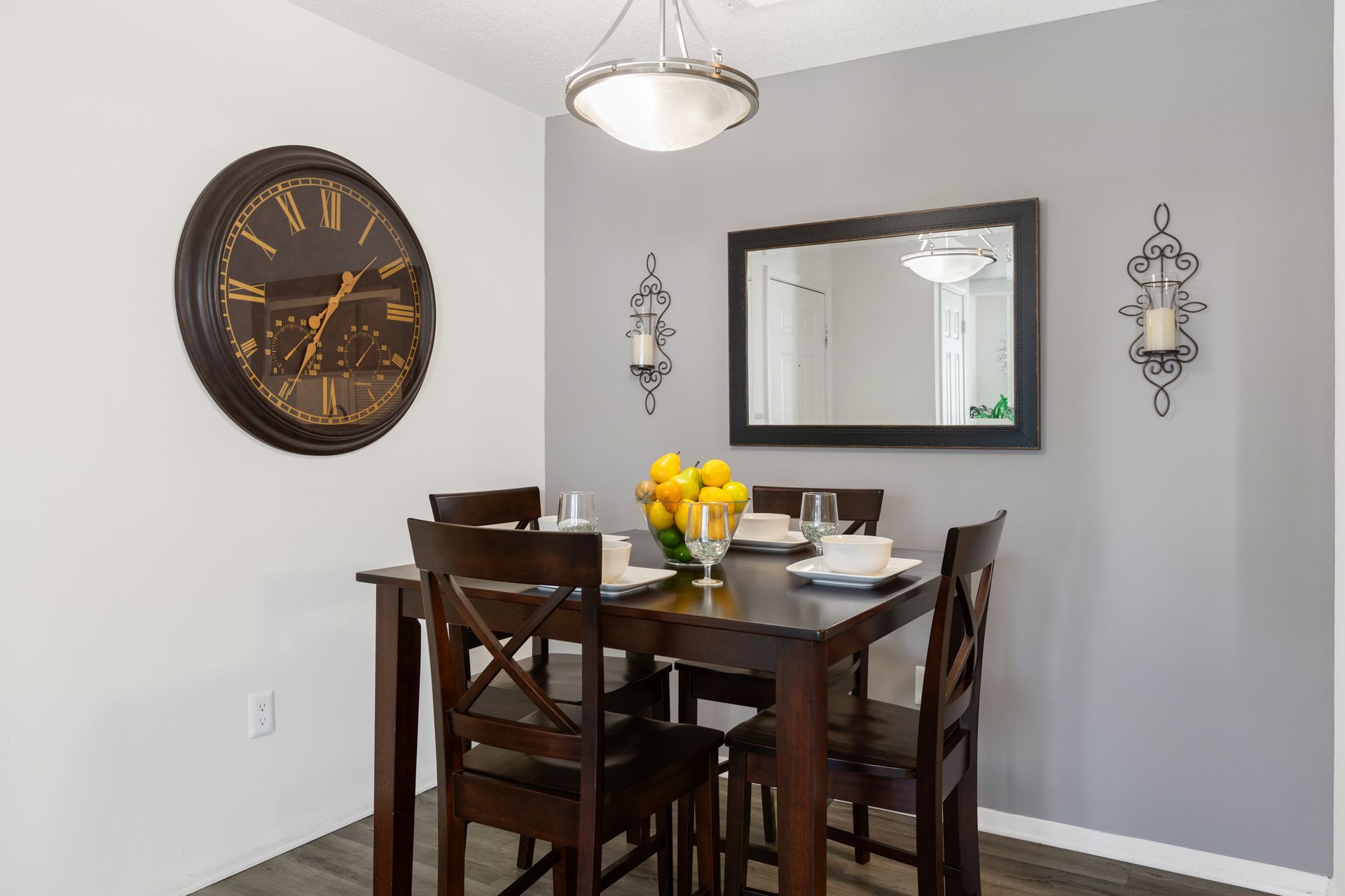 A dining room with a table and chairs and a clock on the wall.