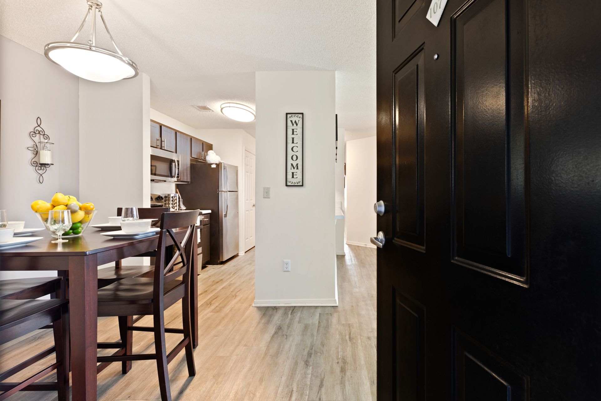 A black door is open to a dining room with a table and chairs