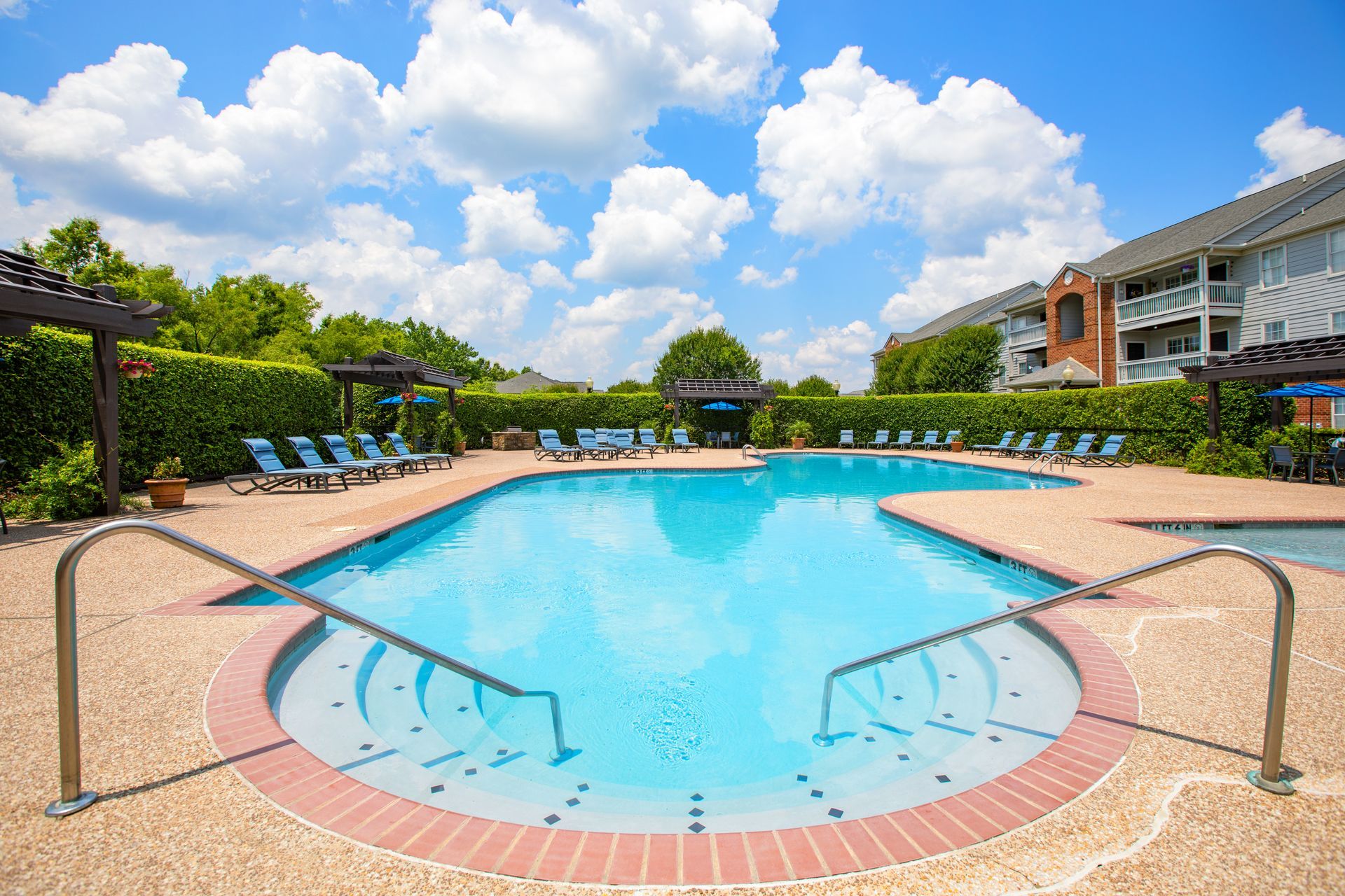 A large swimming pool with stairs leading to it in front of a building.