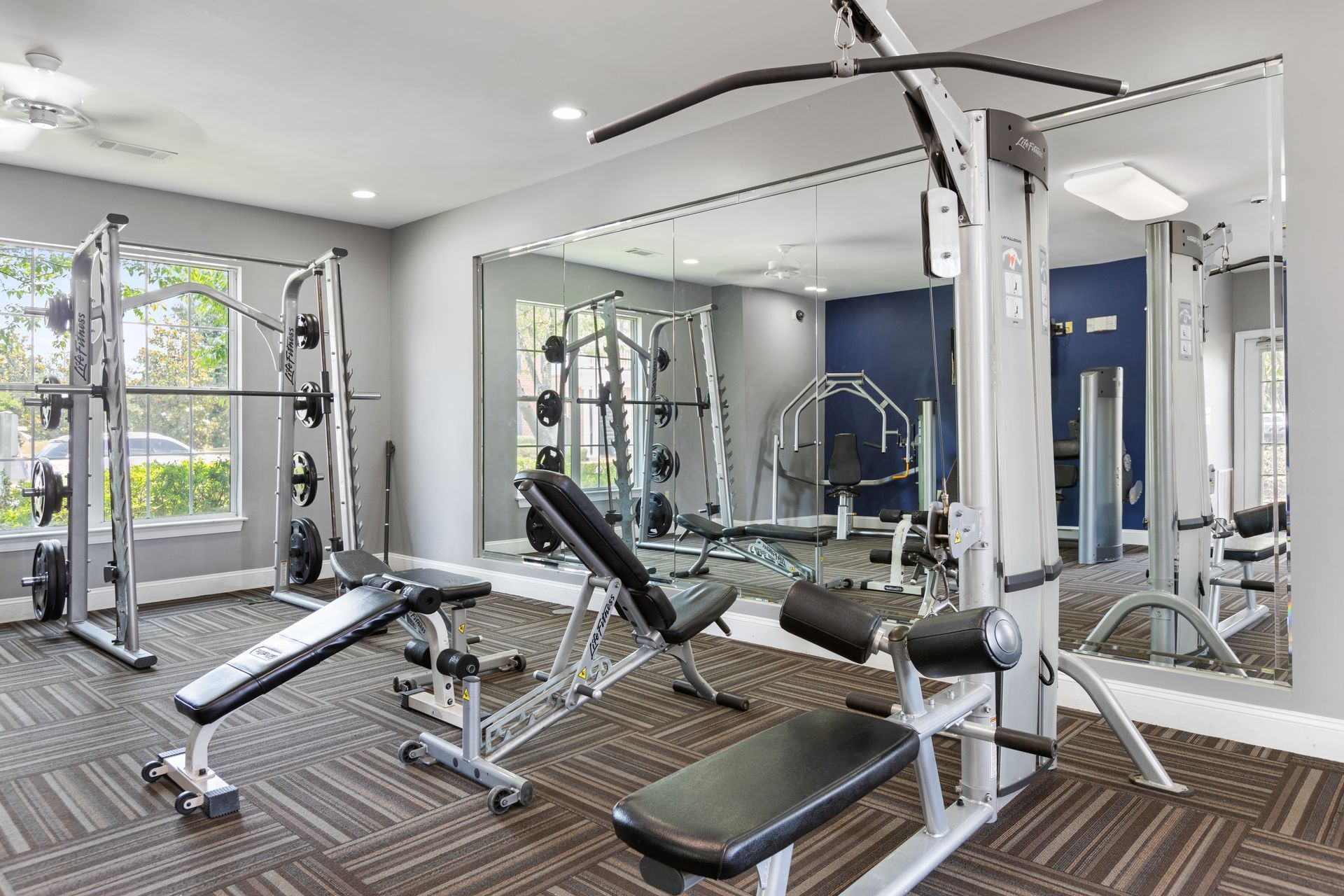 A gym with a lot of exercise equipment and a lot of mirrors.