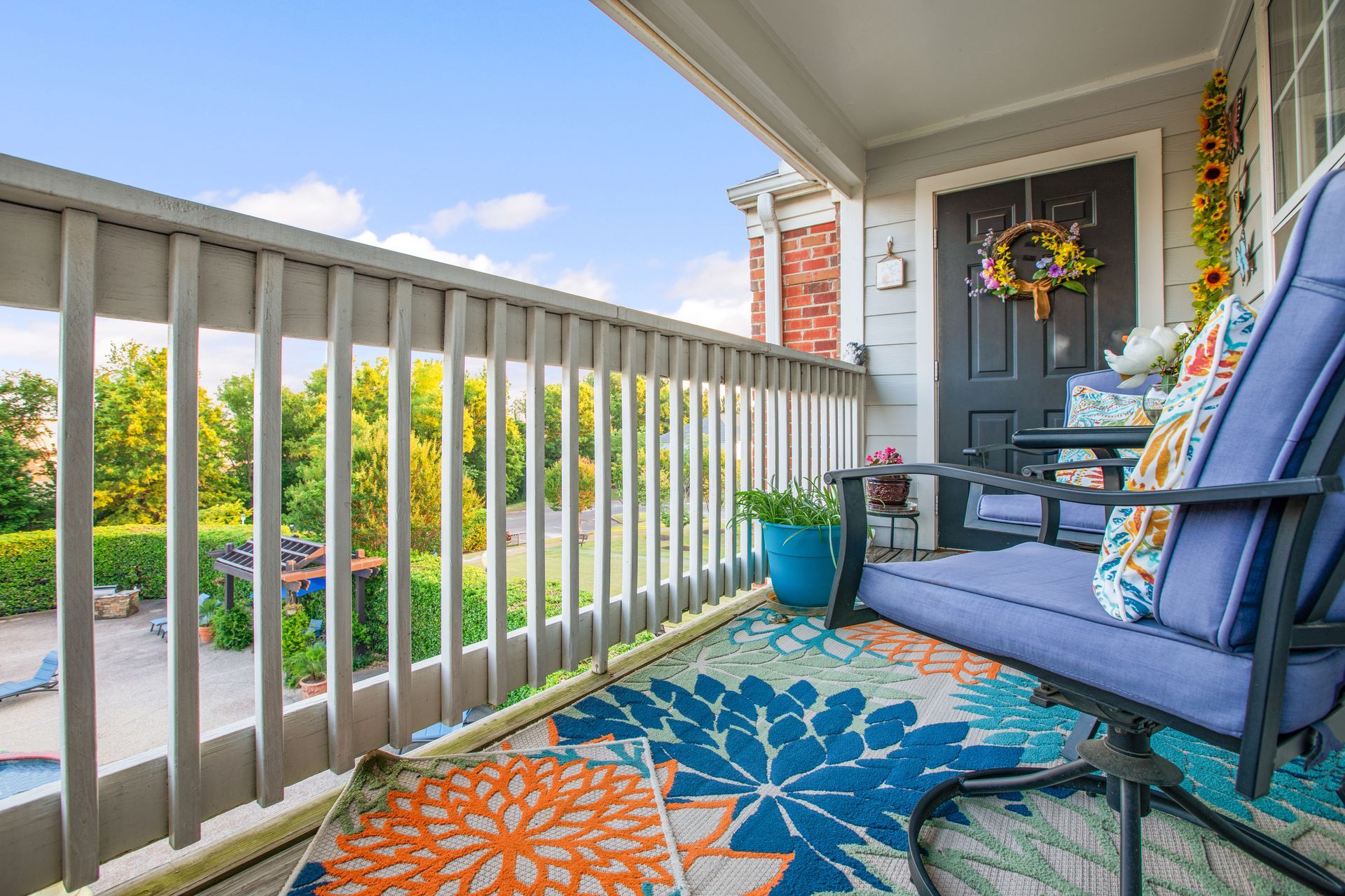 A porch with a couch and chairs and a rug.