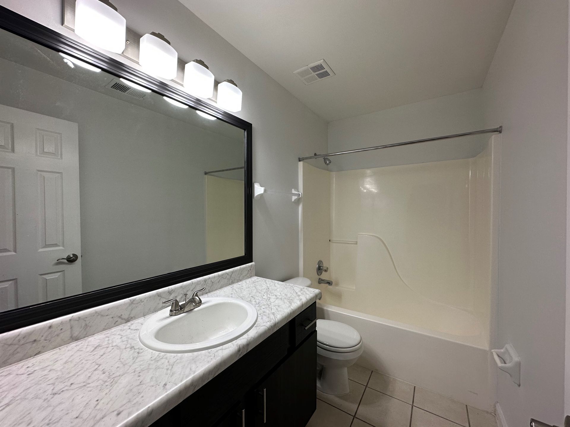 A bathroom with a sink , toilet , shower and mirror.