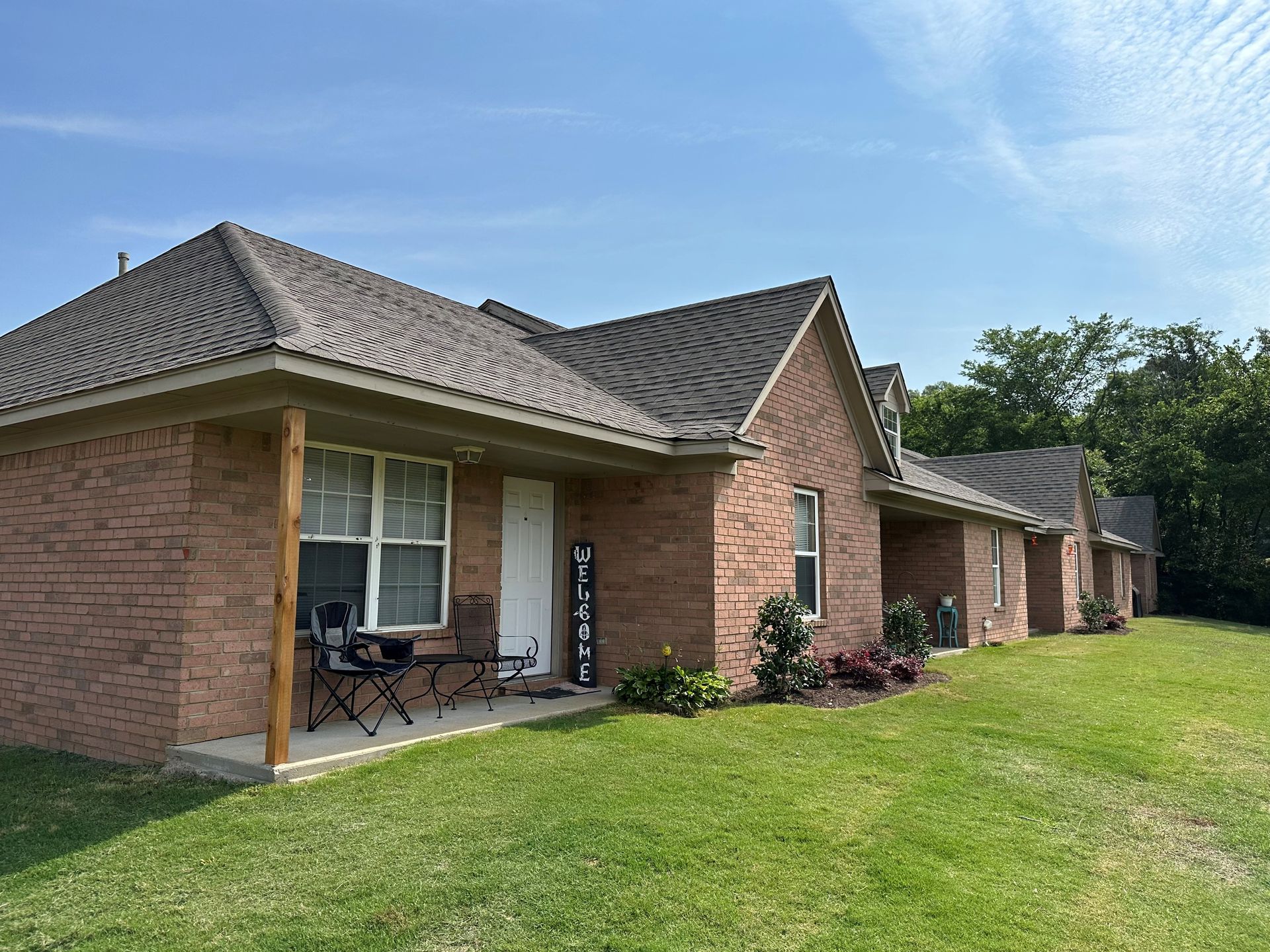 A brick house with a porch and chairs in front of it.