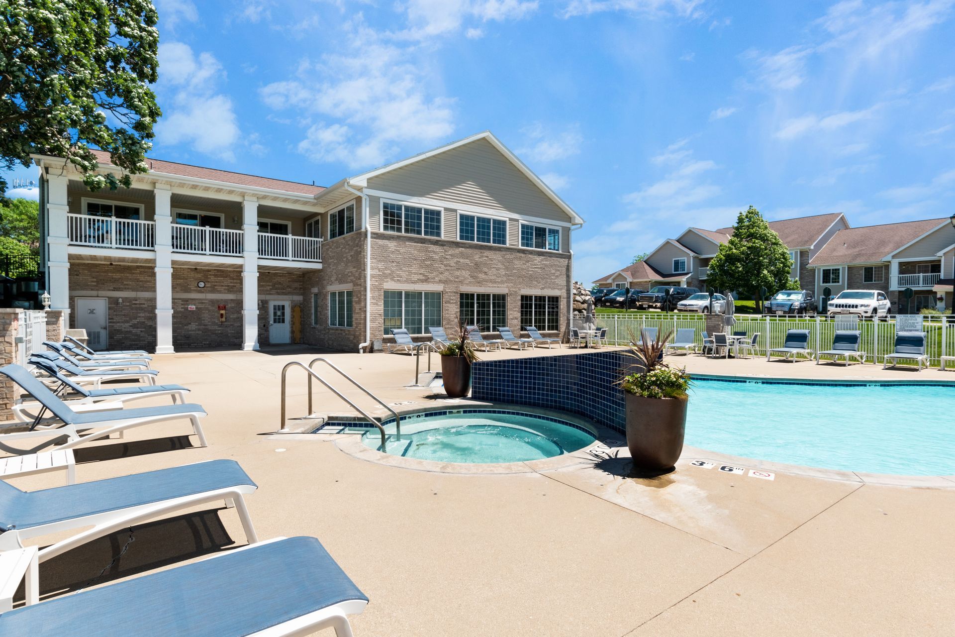 A large swimming pool with a hot tub in front of a large house.
