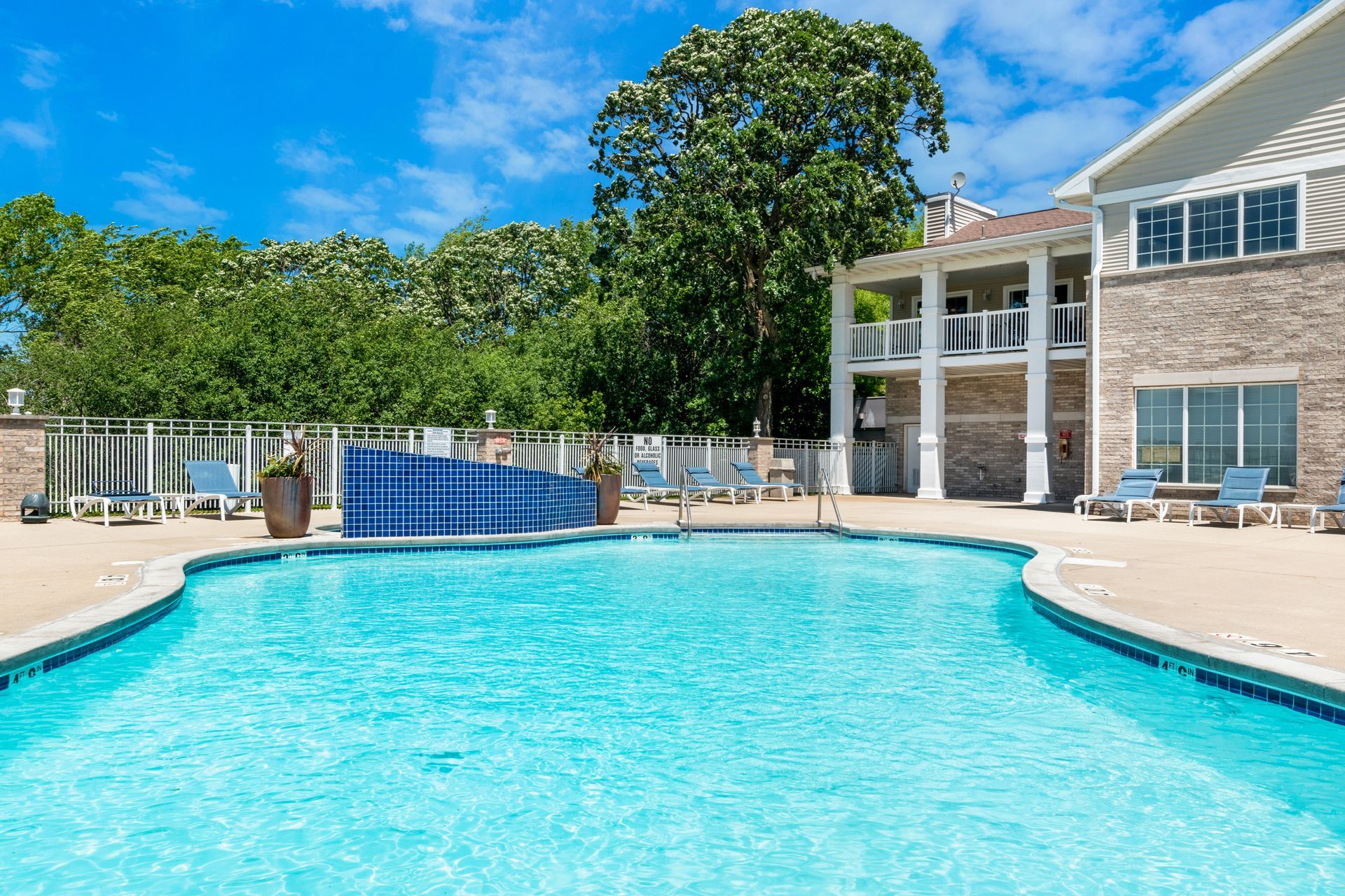 There is a large swimming pool in front of a house.