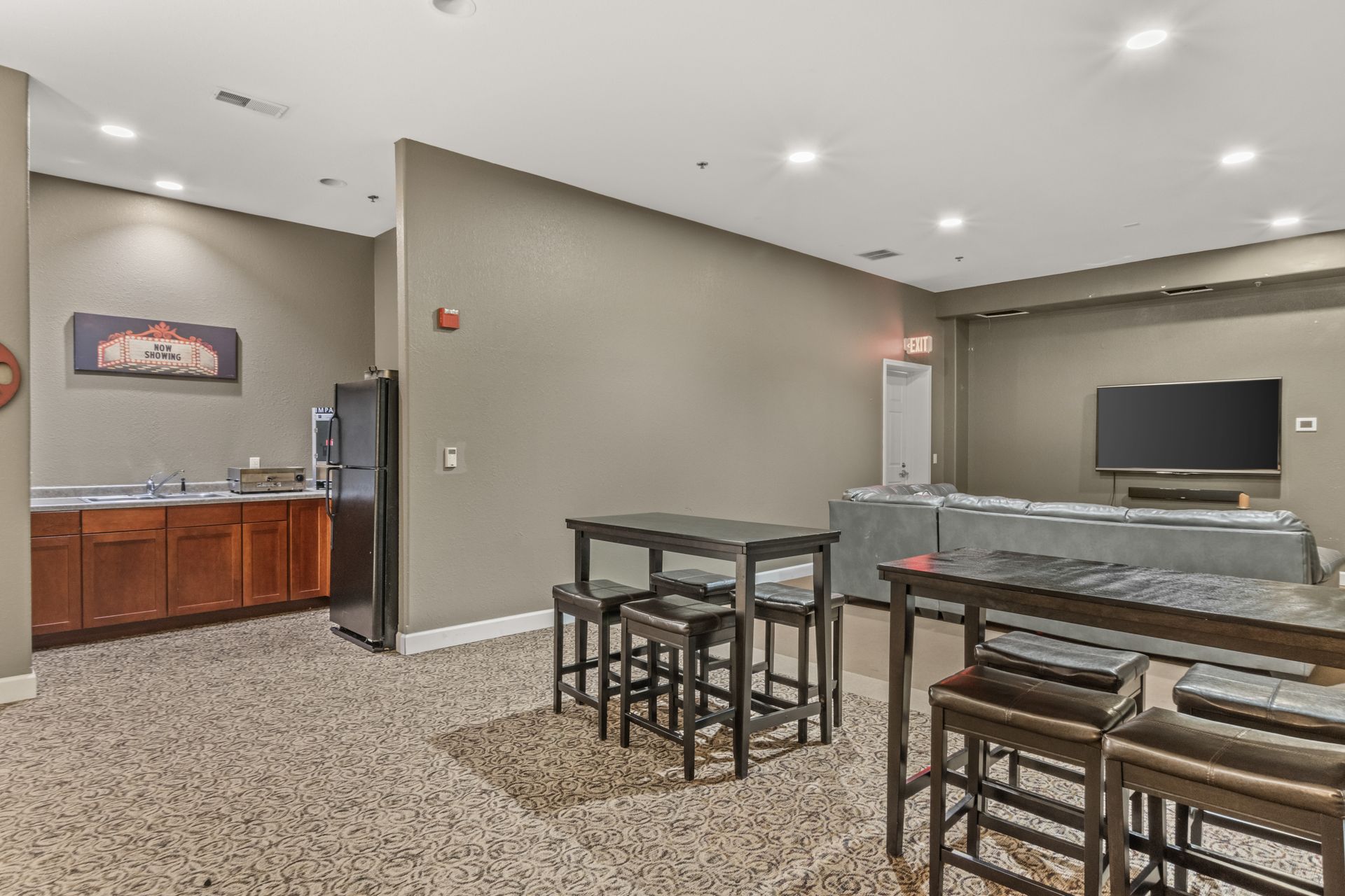 A living room with a table and stools and a flat screen tv.