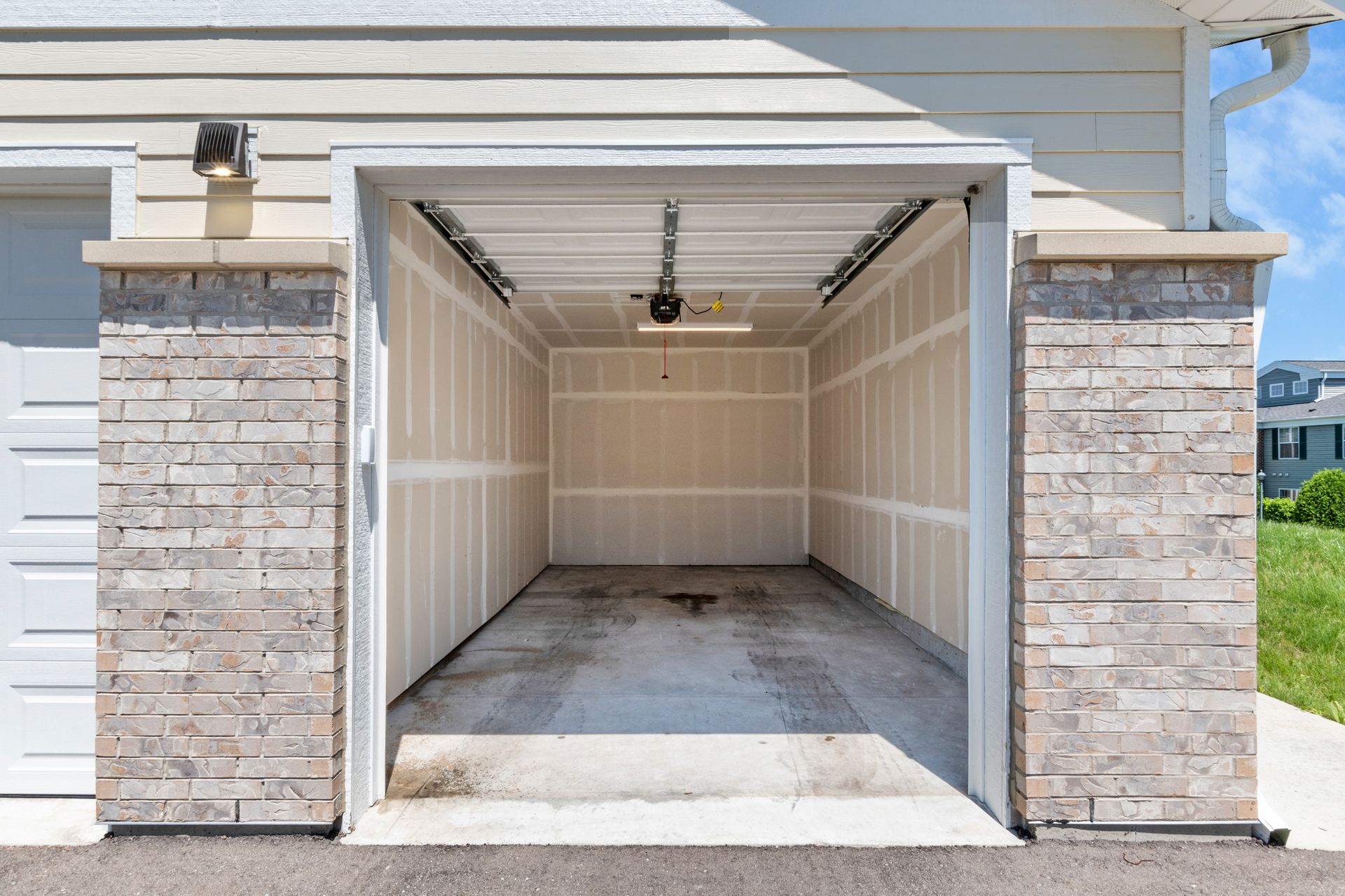 An empty garage with the door open and a brick wall.
