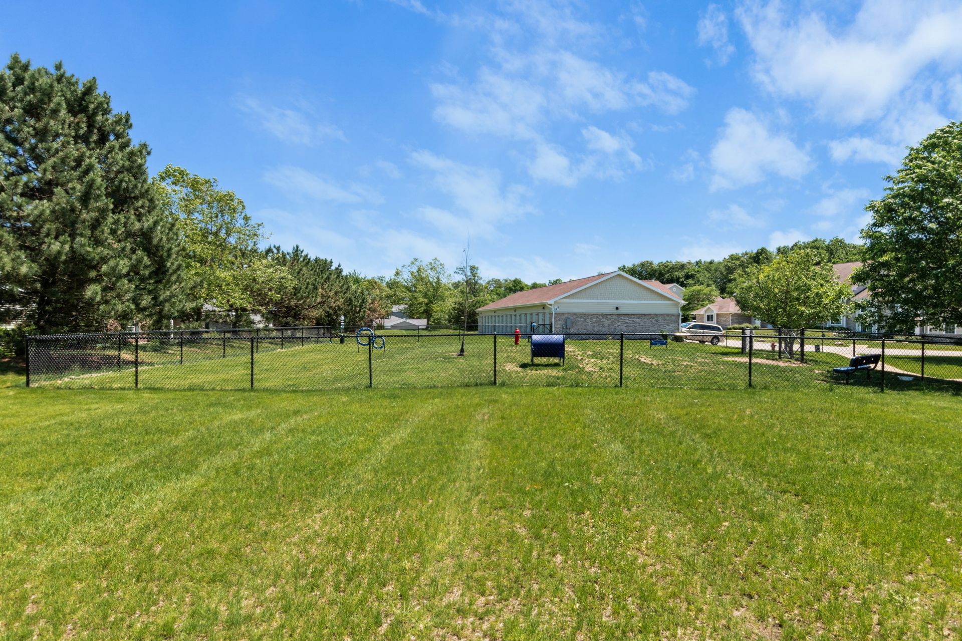 A large grassy field with a fence around it and a house in the background.