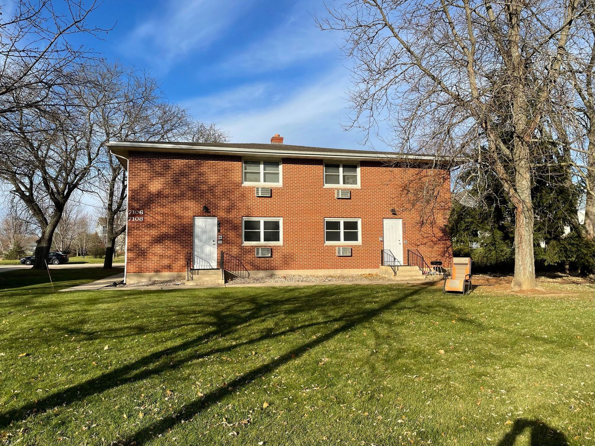 A large brick house is sitting in the middle of a lush green field.