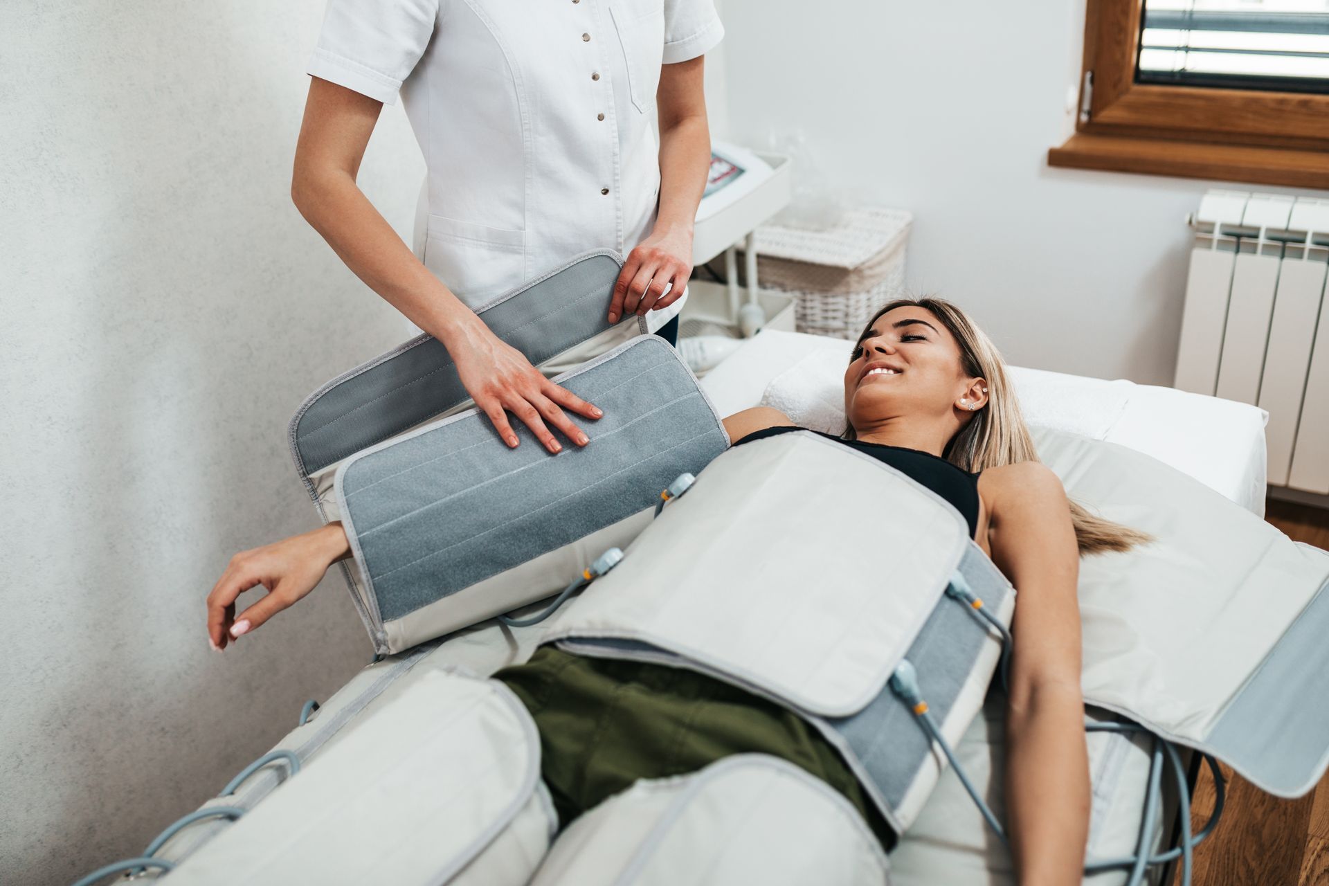 Una donna è sdraiata su un letto mentre si sottopone a un trattamento di drenaggio linfatico.