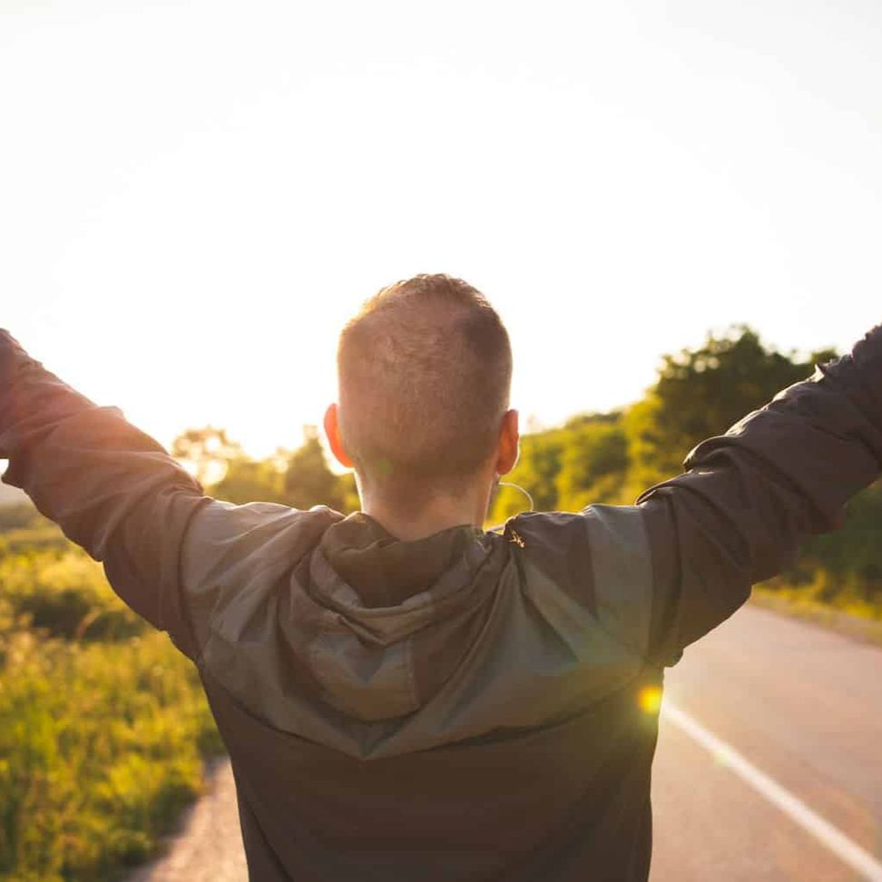 Man raising his arms facing the sun showing he is motivated.