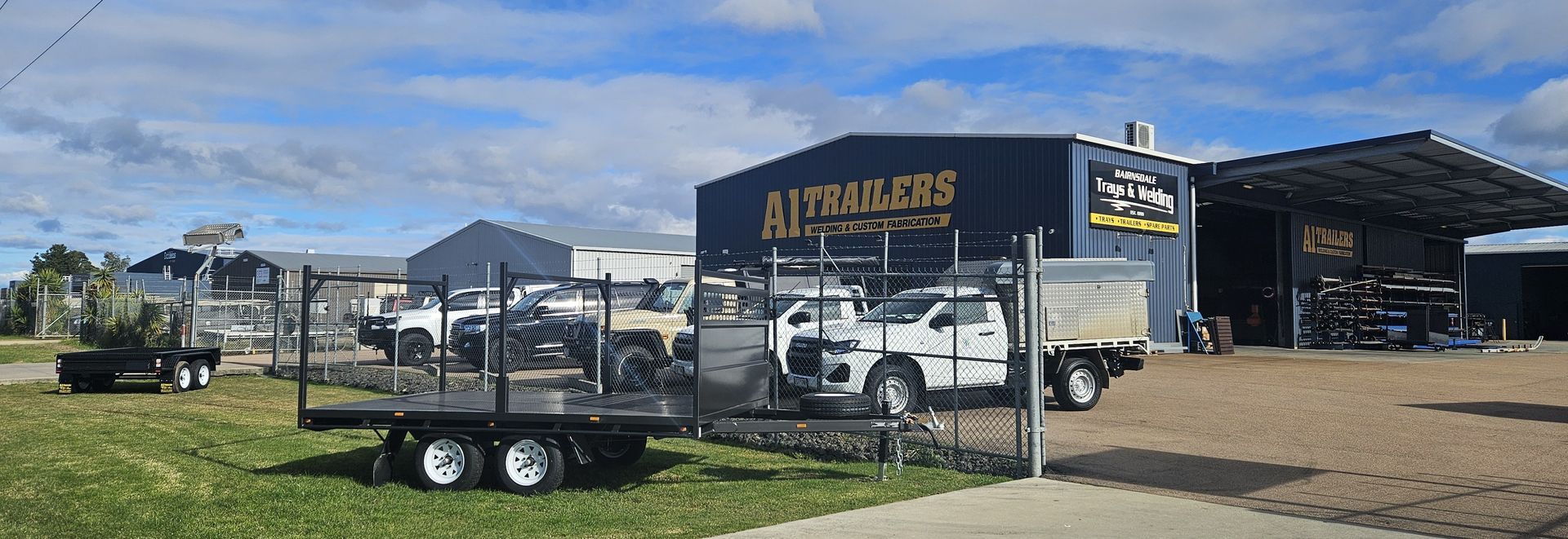 A white truck is parked in front of a building that says ai trailers welding and custom fabrication.