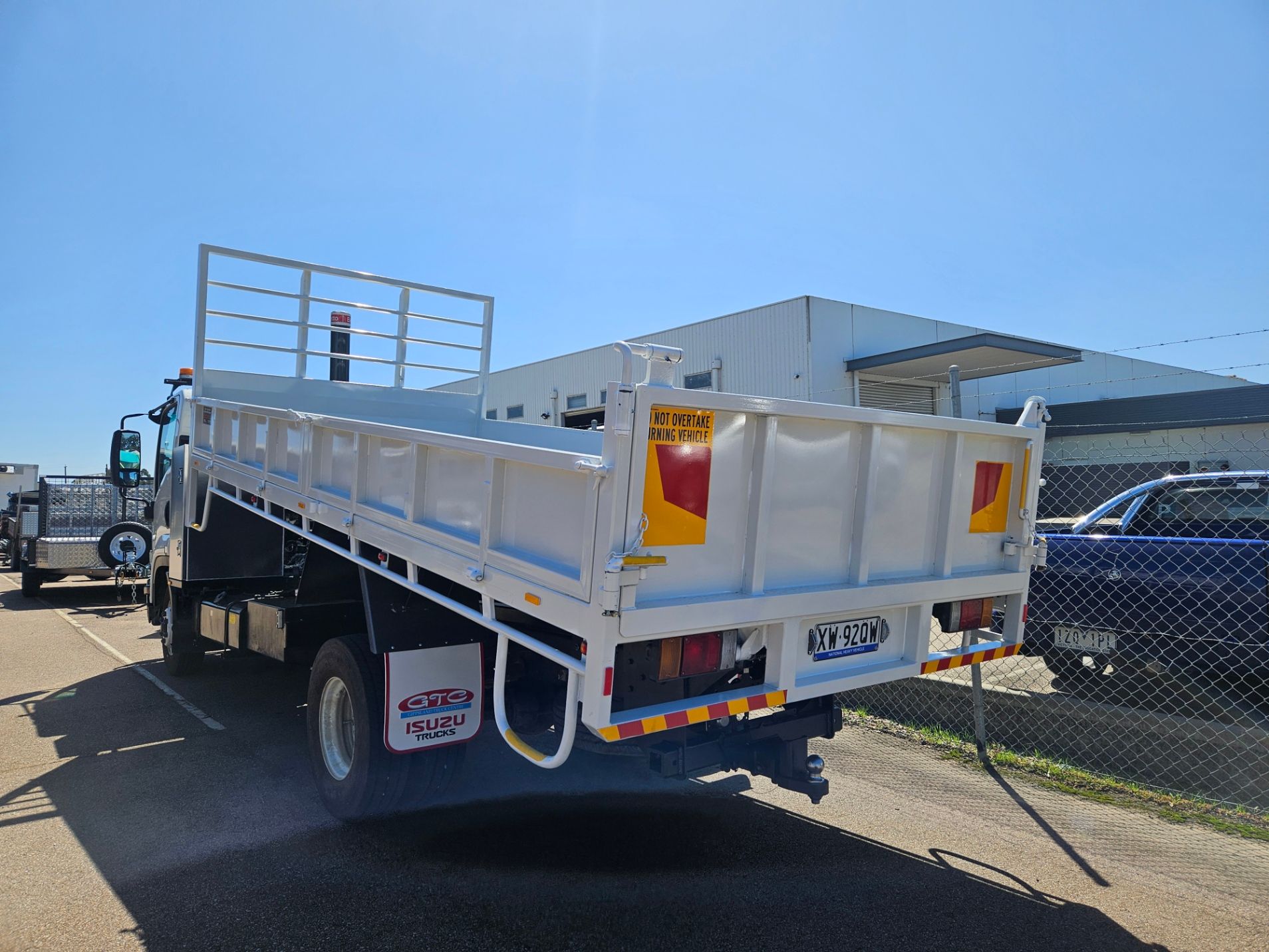 White dump truck parked on asphalt. Rear view, sunny day.