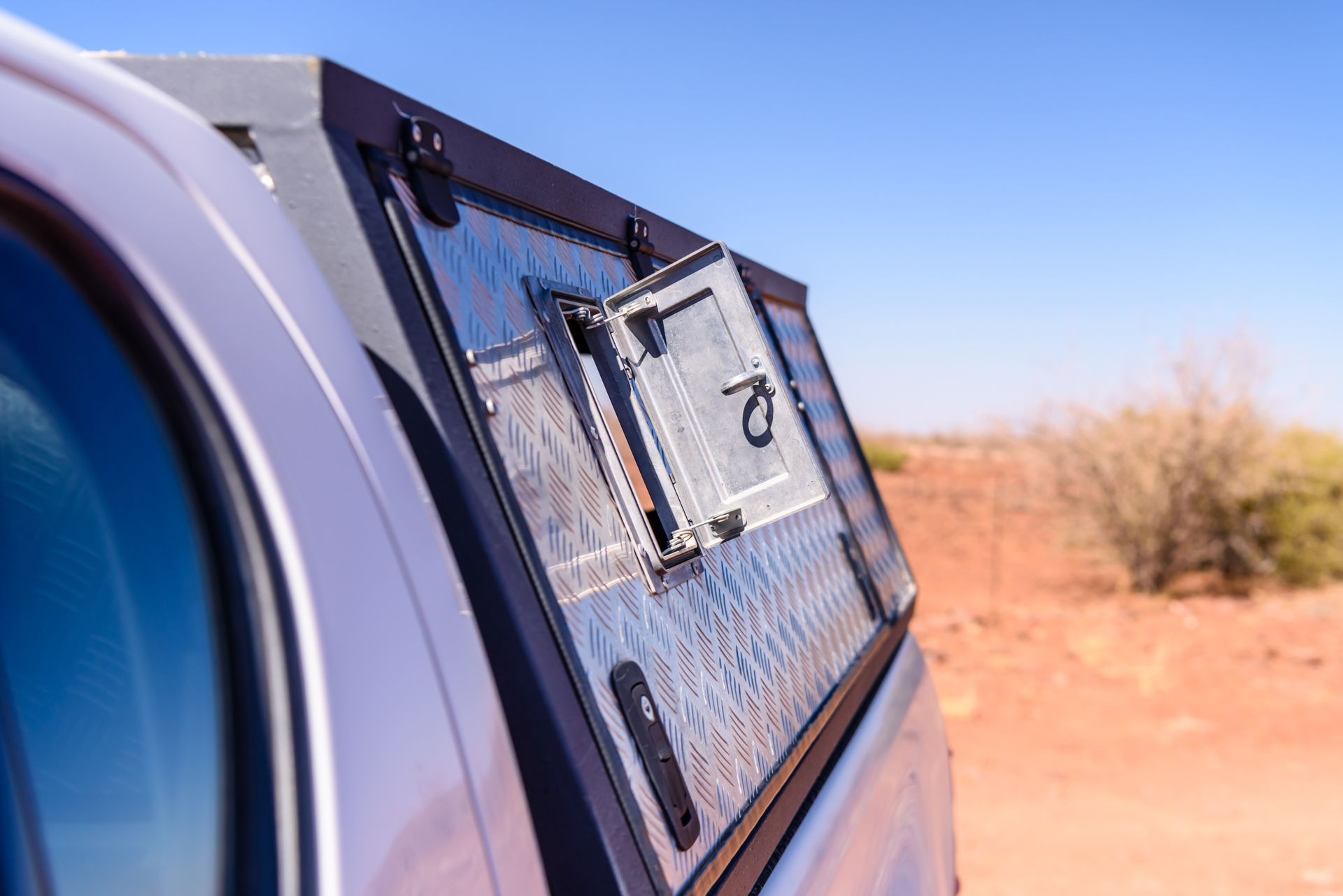 A close-up of an open flap on the side of a pickup truck canopy.