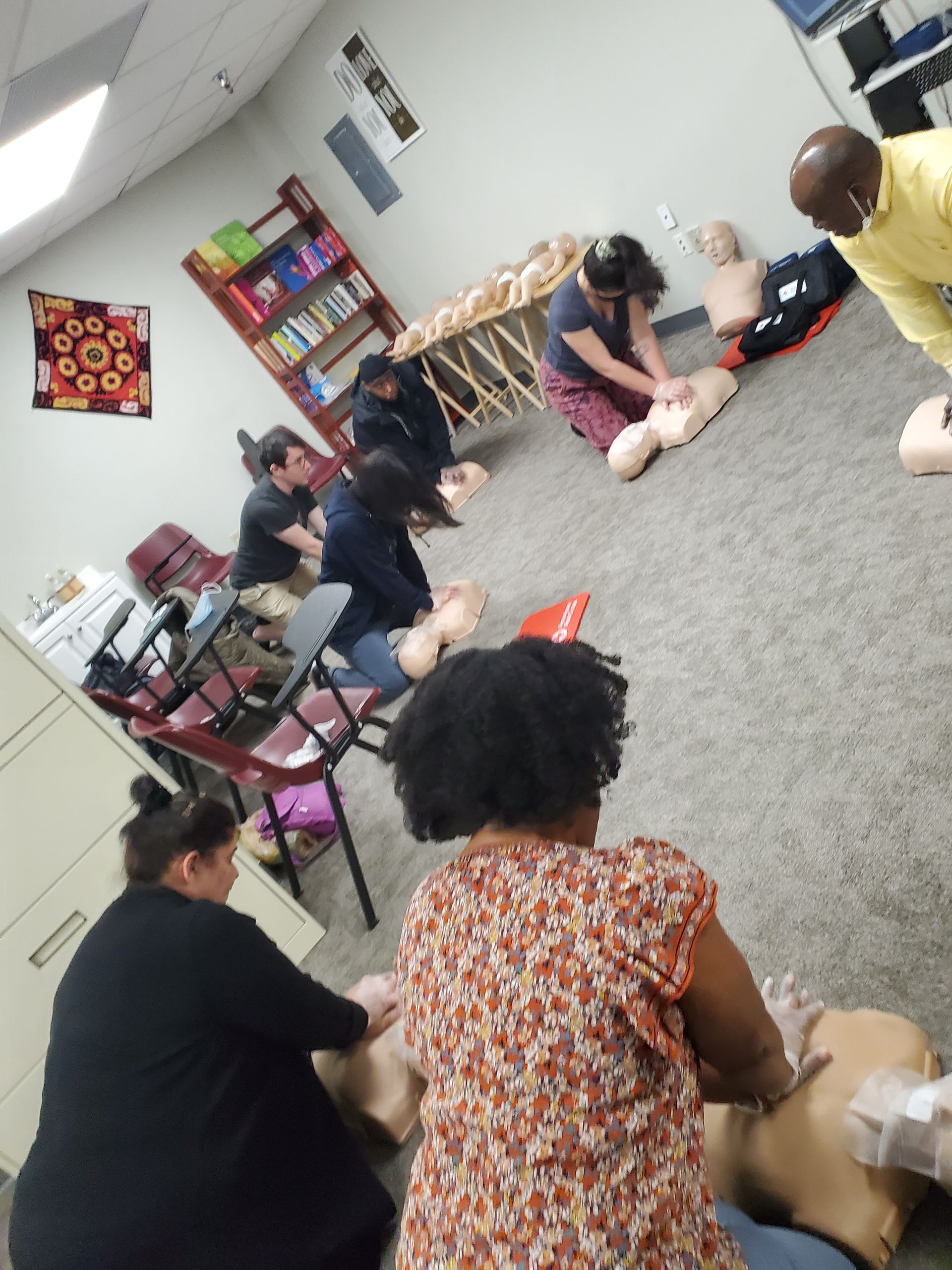 A group of people are practicing on a mannequin