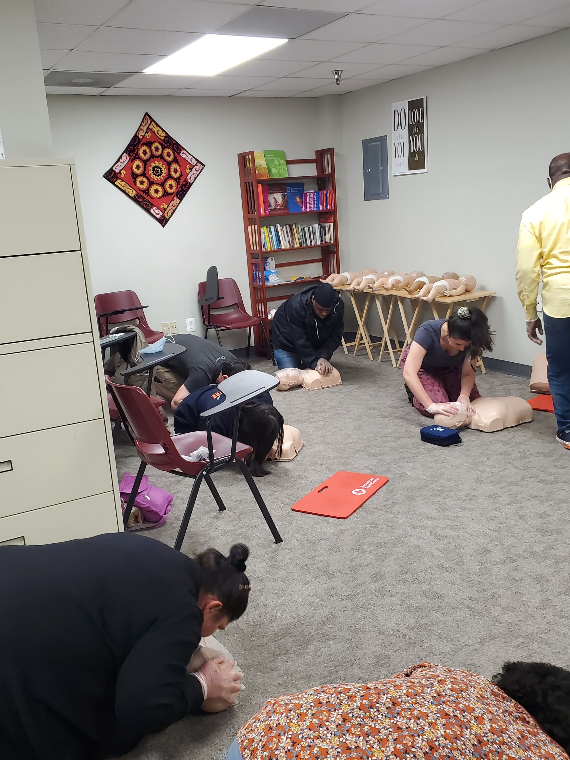 A group of people are practicing first aid in a room.