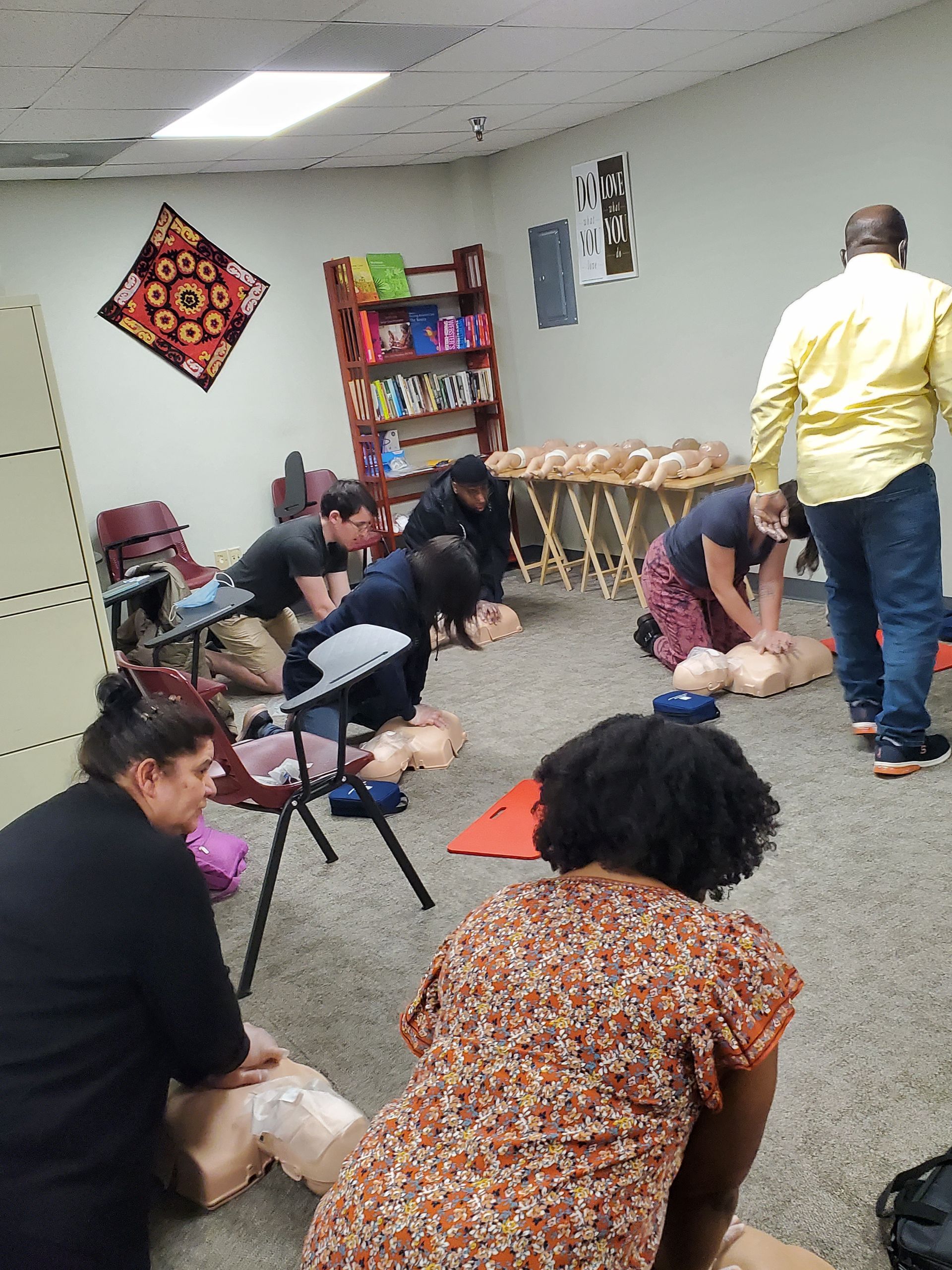 A group of people are practicing first aid in a room.