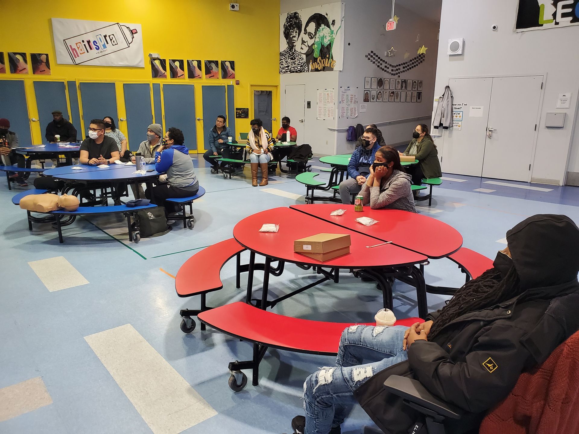 A group of people are sitting at red tables in a room