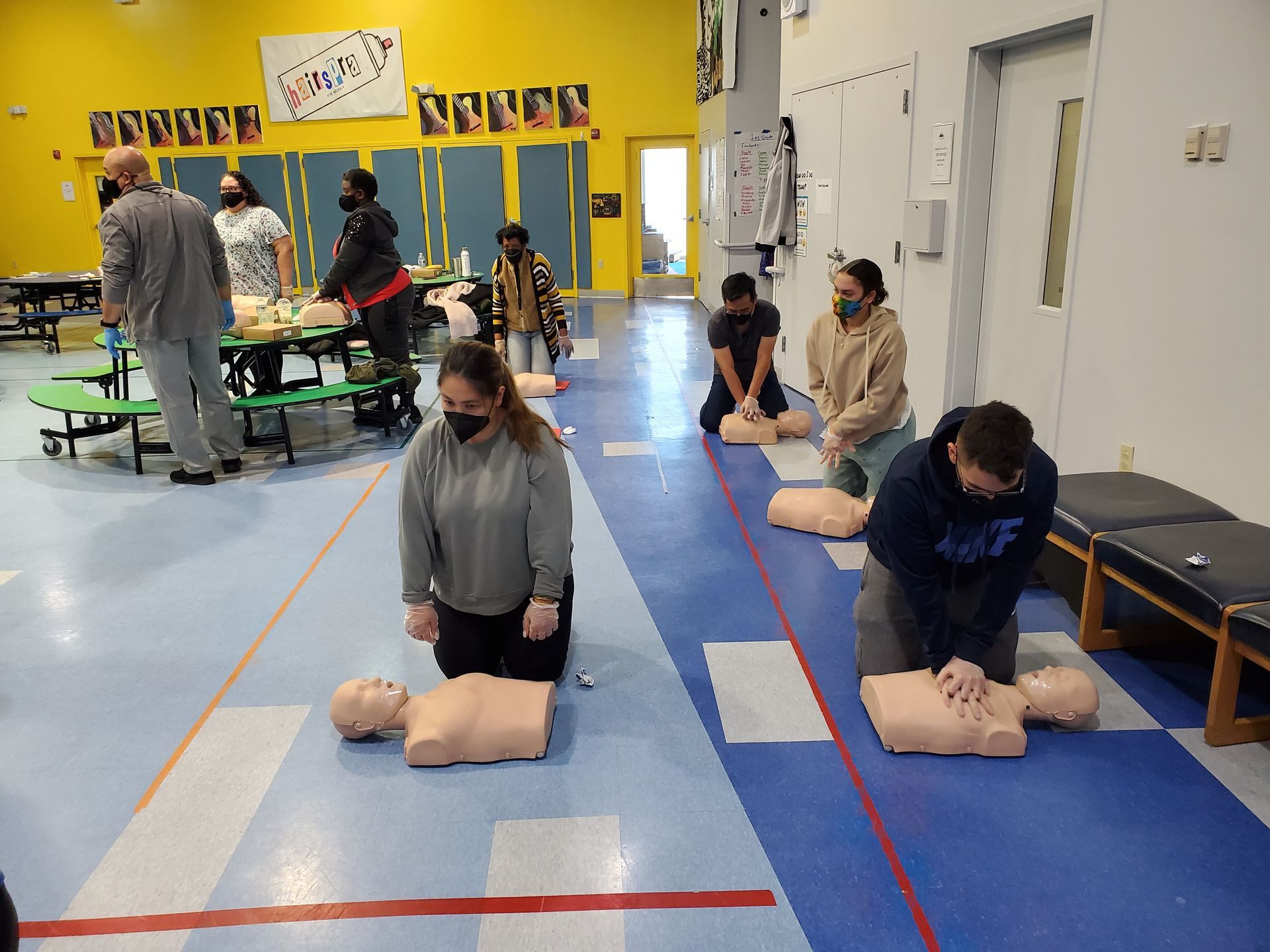 A group of people are practicing first aid on a mannequin in a gym.