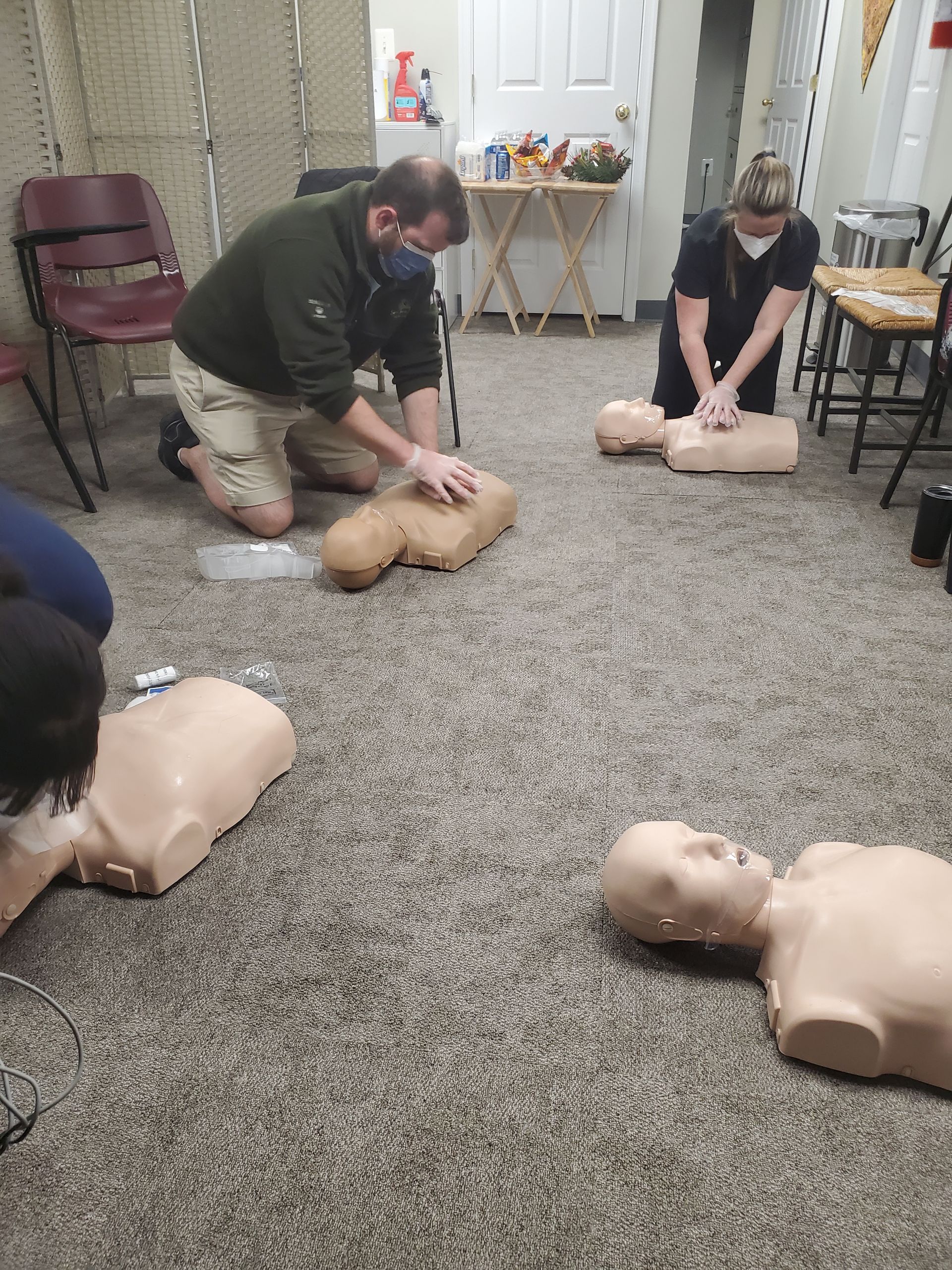A group of people are practicing first aid on mannequins.