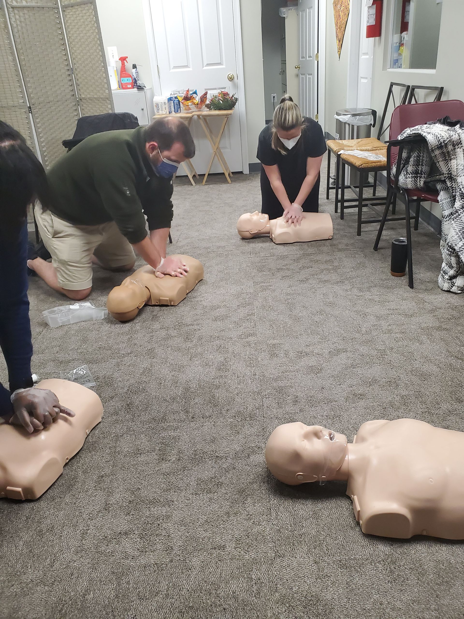 A group of people are practicing a cpr on a mannequin.