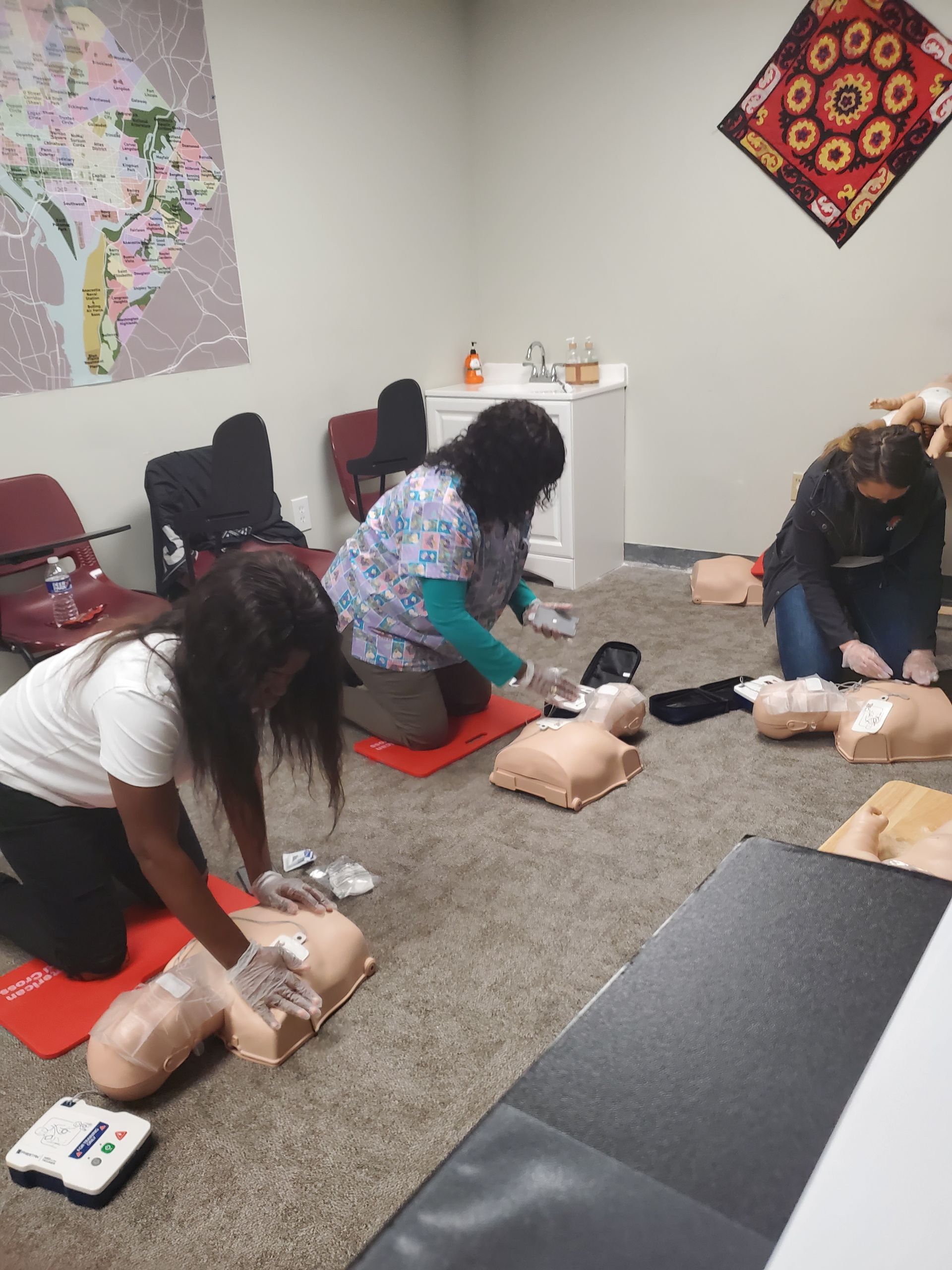 A group of people are doing a cpr on a mannequin in a room.