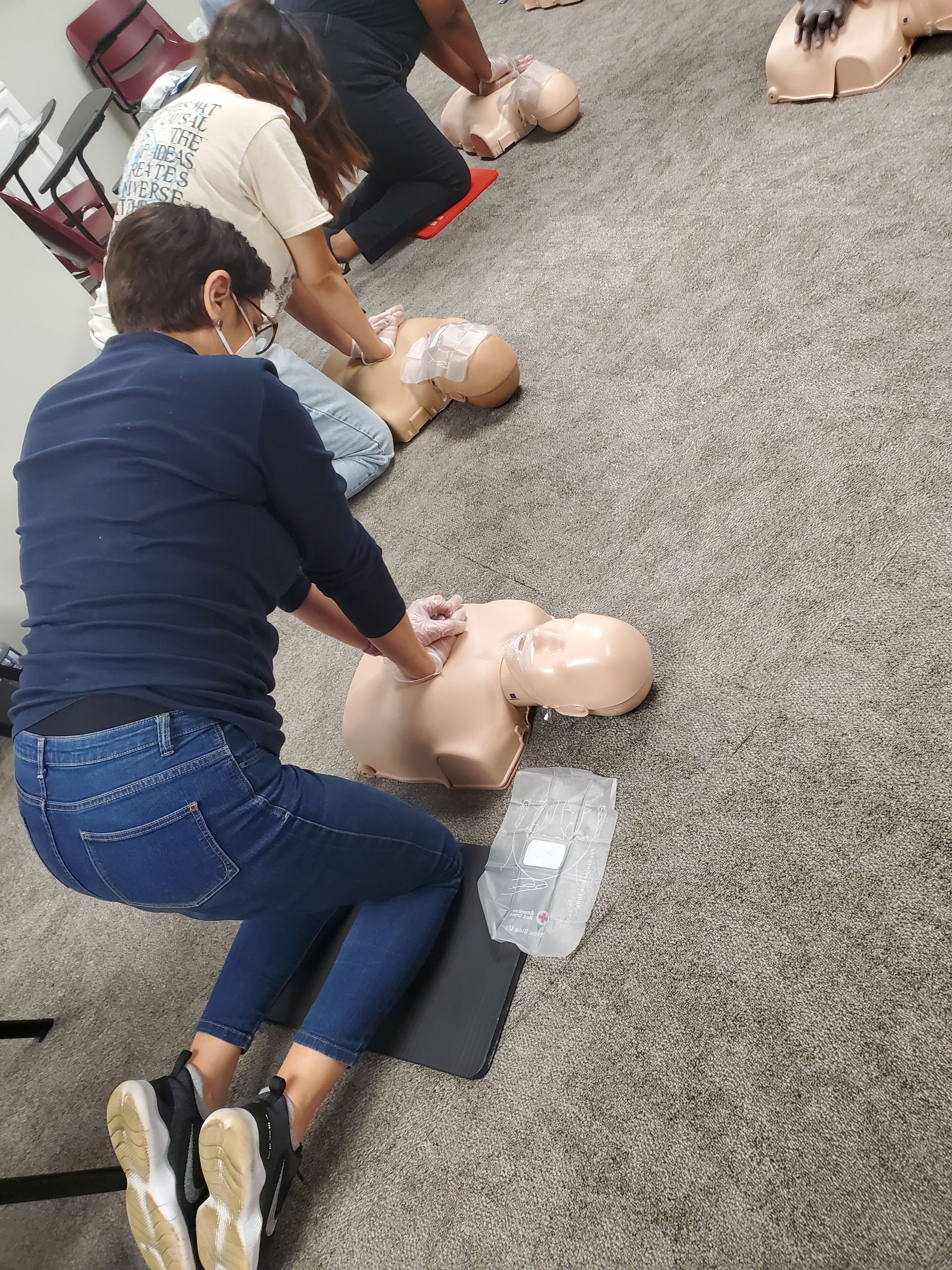 A group of people are practicing a cpr on a mannequin.