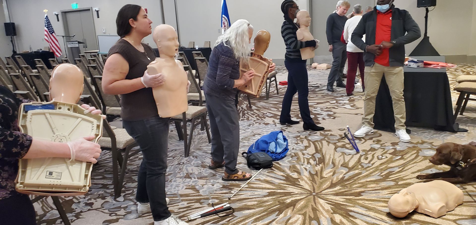A group of people are standing around a mannequin in a room.