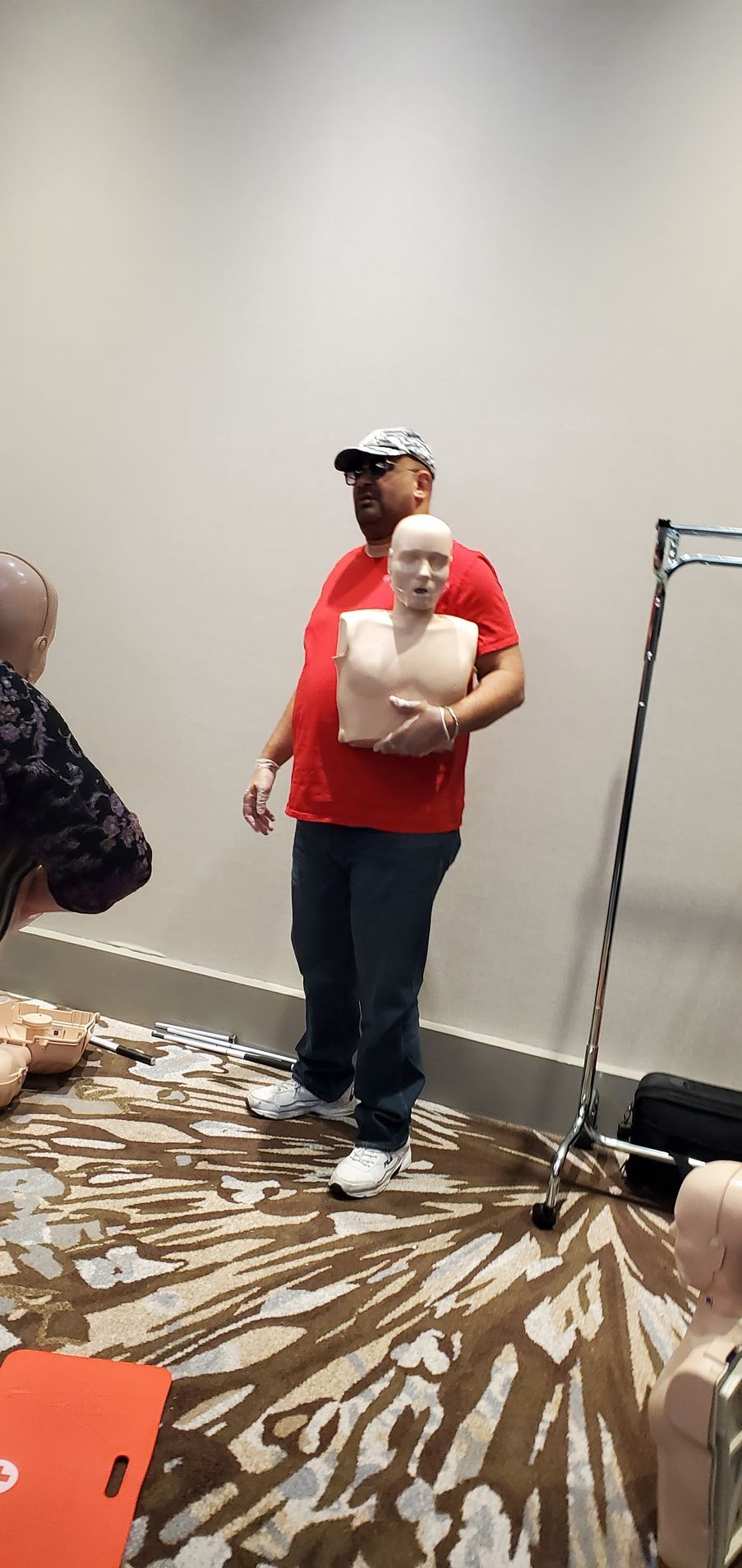 A man in a red shirt is holding a mannequin in a room.