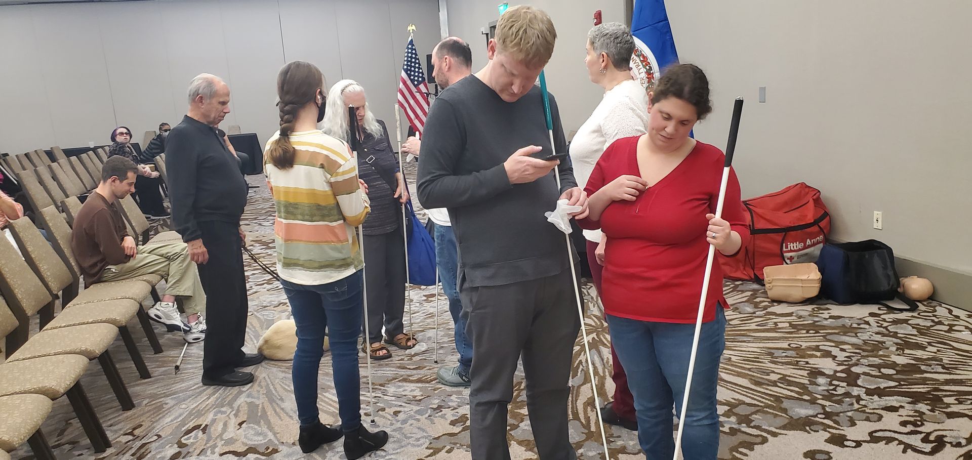 A group of people are standing in a room looking at their phones.